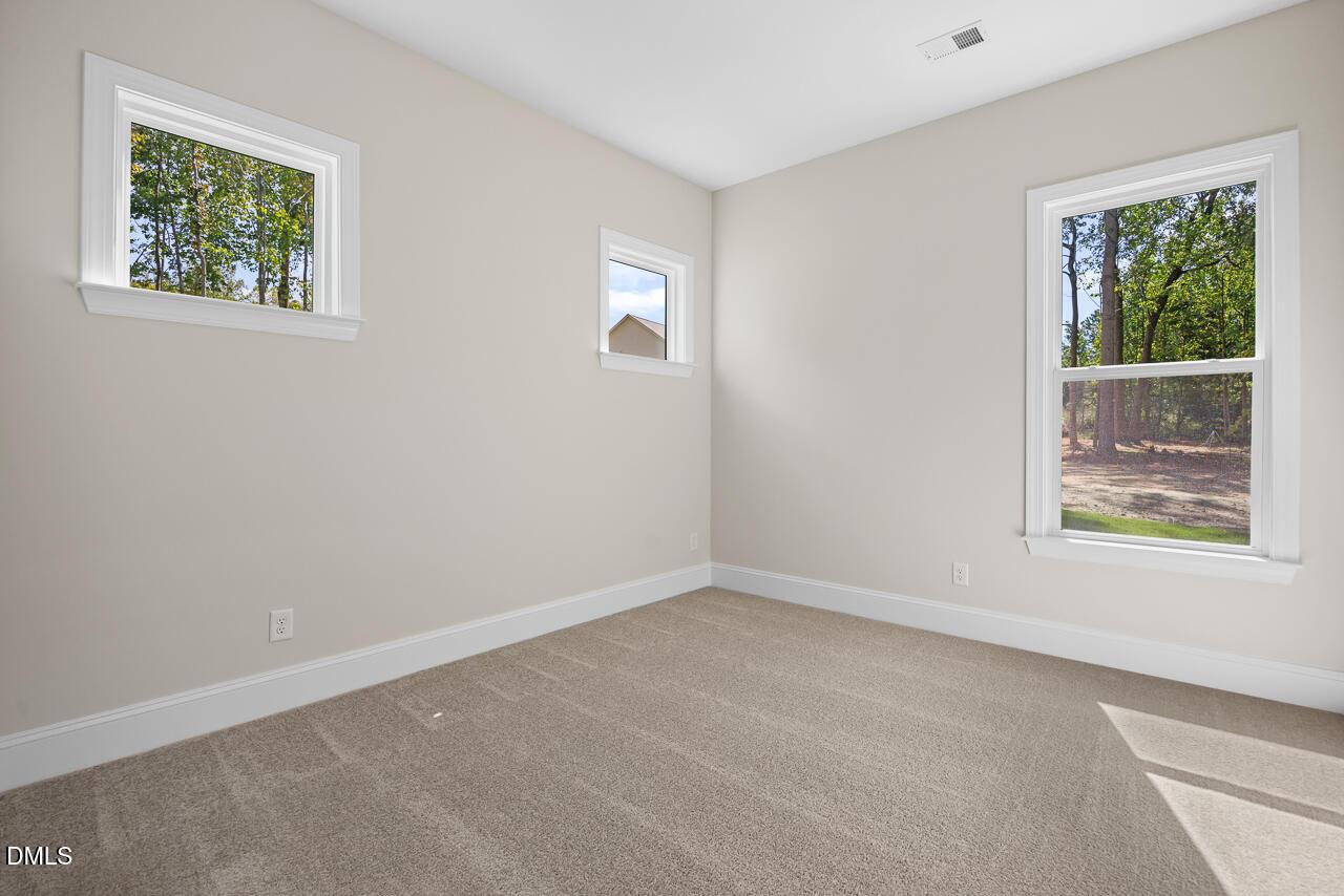 Bright carpeted bedroom with multiple windows overlooking wooded views in Davidson Homes The Crawford D, Rockport, Wake Forest, NC