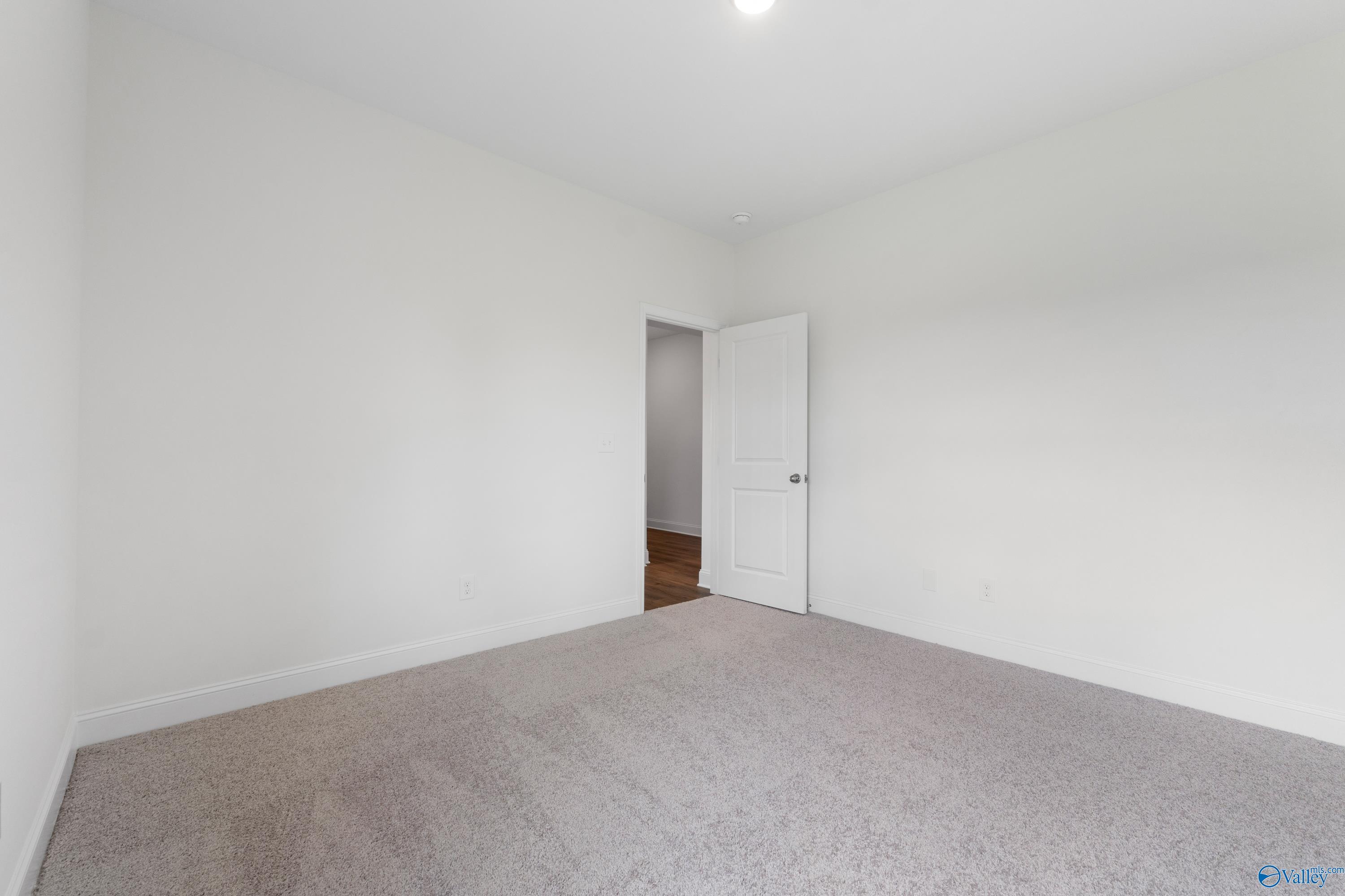 Bright, carpeted bedroom with neutral walls in The Everett B floor plan at The Meadows in Athens, Alabama.