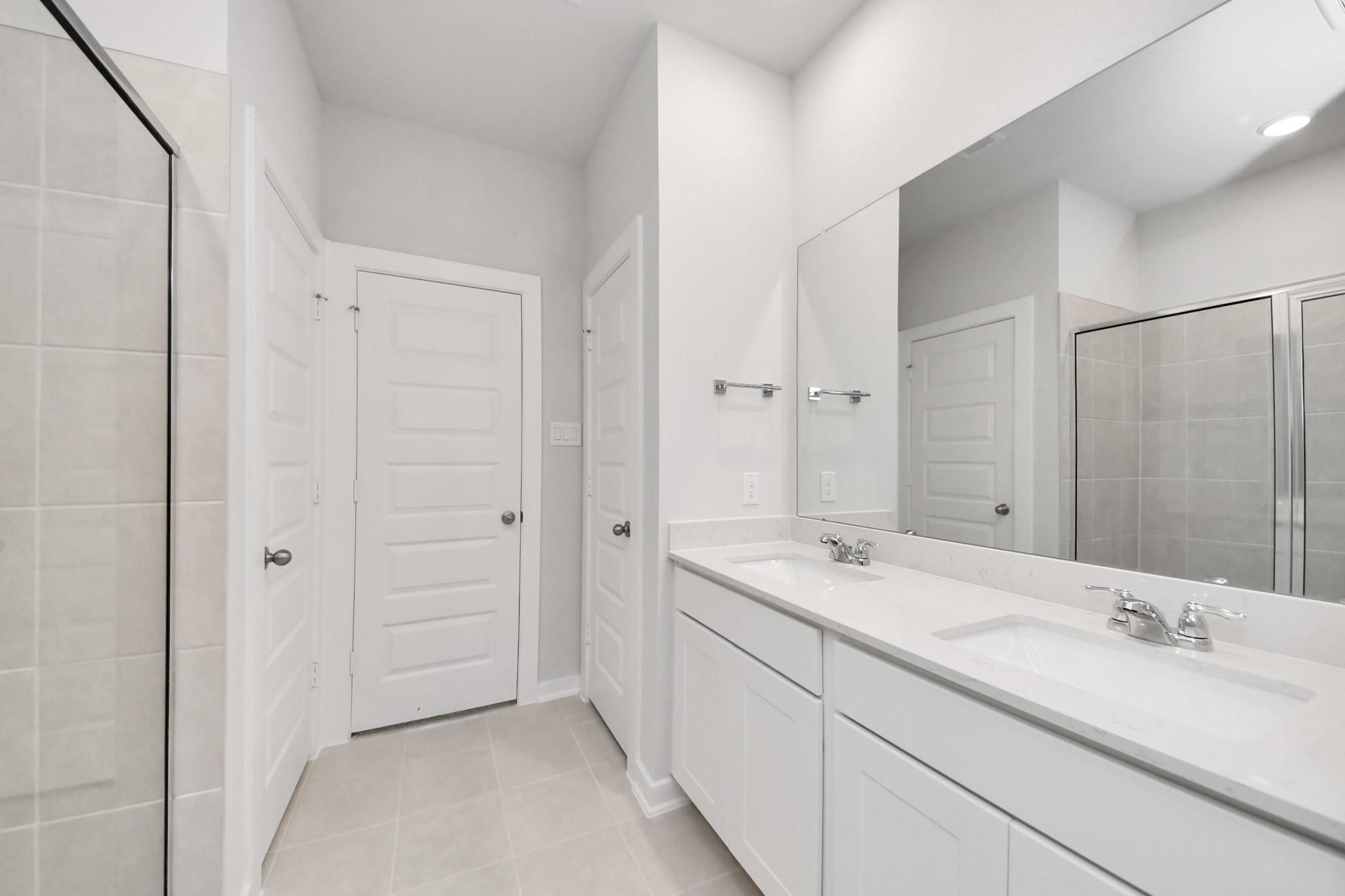 Modern primary bathroom with double vanity and walk-in shower in The Blanco E floor plan at Caney Creek Place, Conroe.