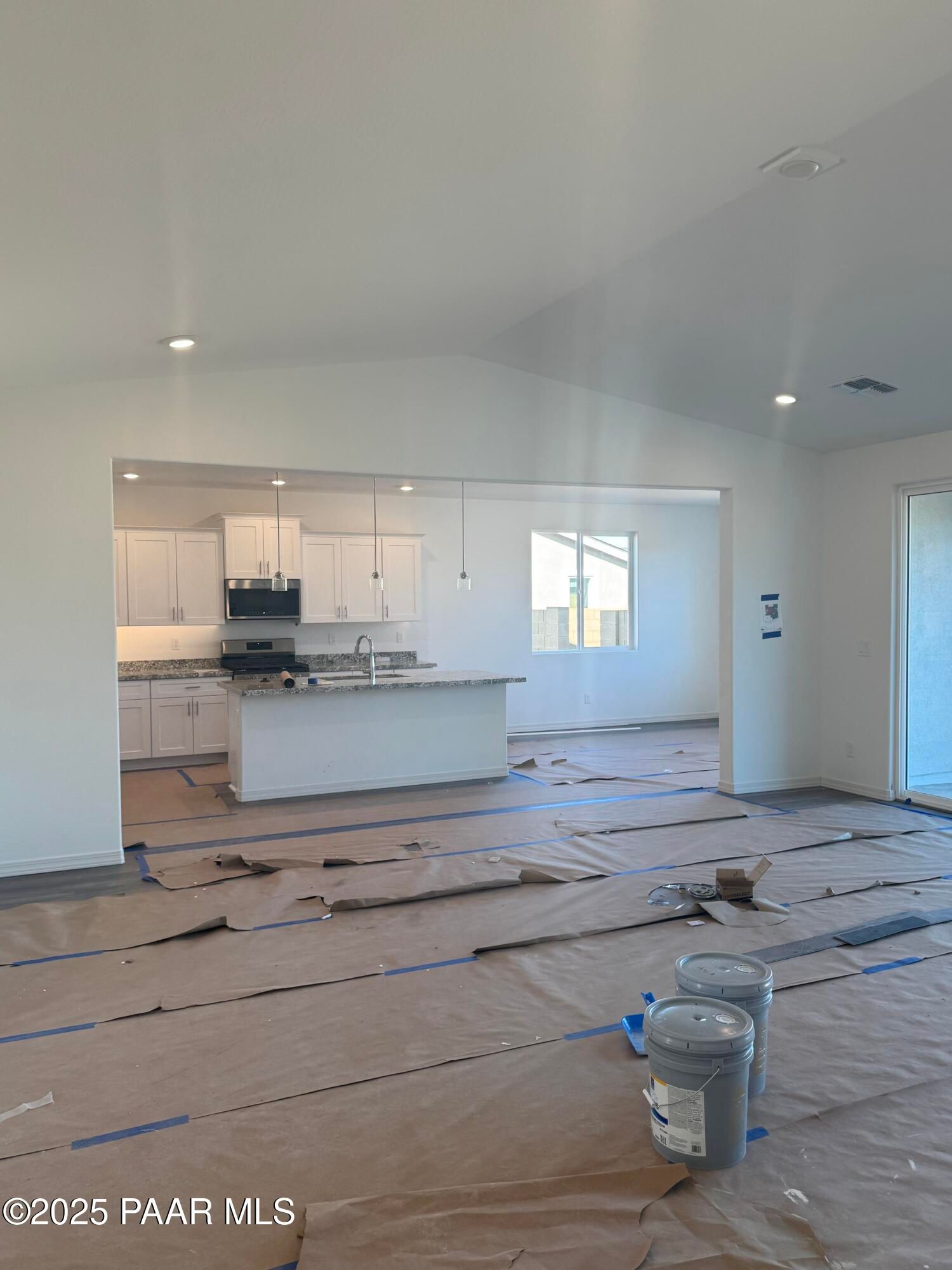 Open-concept kitchen and living area with white island, cabinets, and vaulted ceiling in Davidson Homes The Summit A, Prescott, Arizona