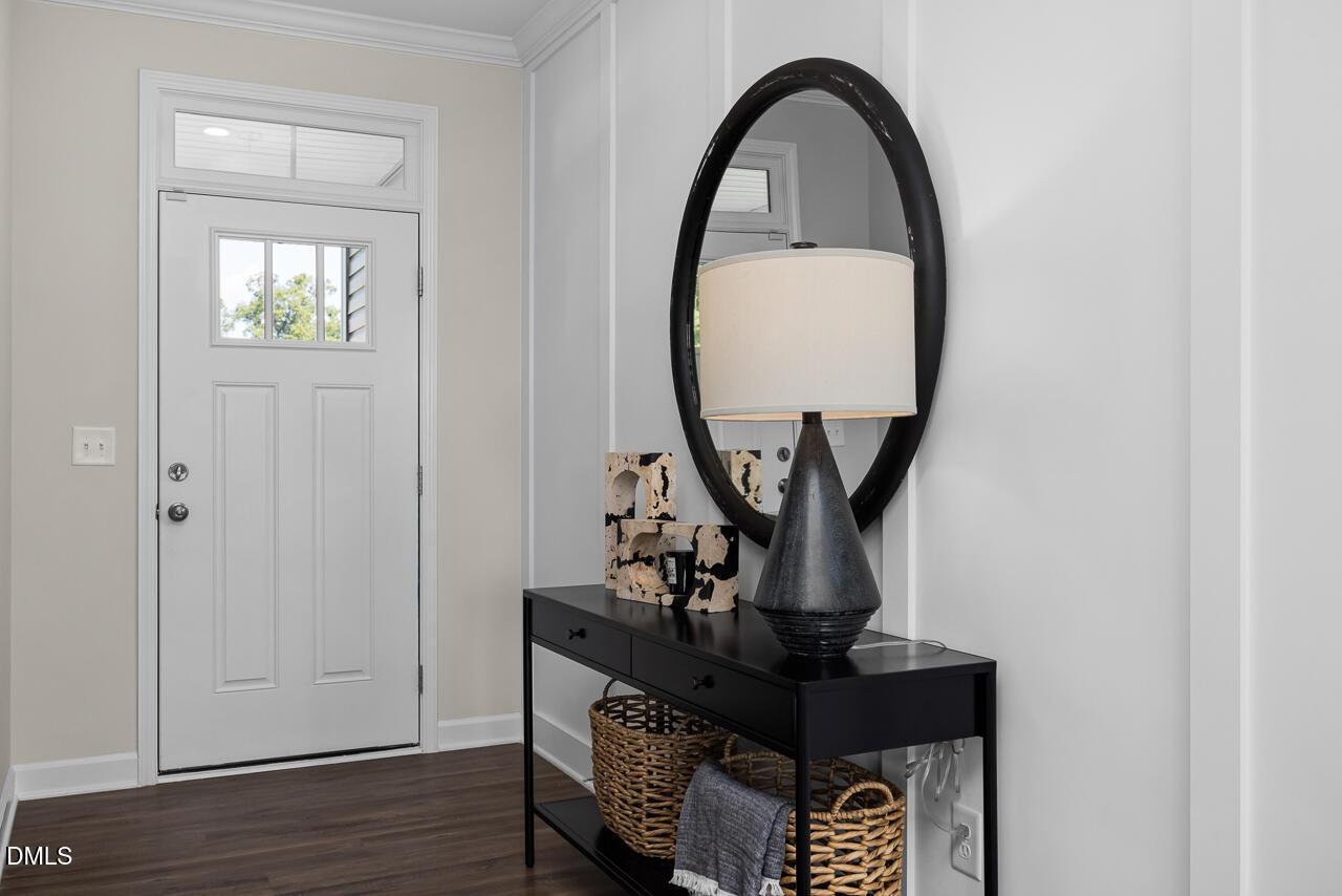 Elegant entryway with large round black mirror, console table, lamp, and hardwood floors in The Hickory II C home, Zebulon, NC