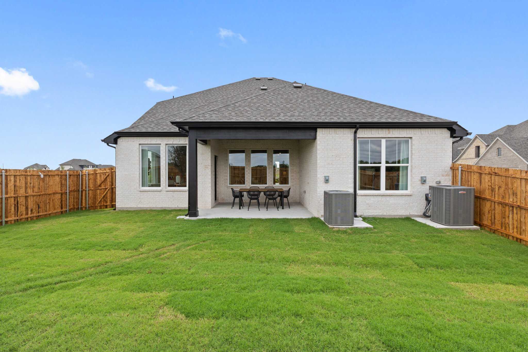 Covered back patio with dining set and large windows overlooking fenced green yard in Davidson Homes Sequoia N, Josephine, Texas