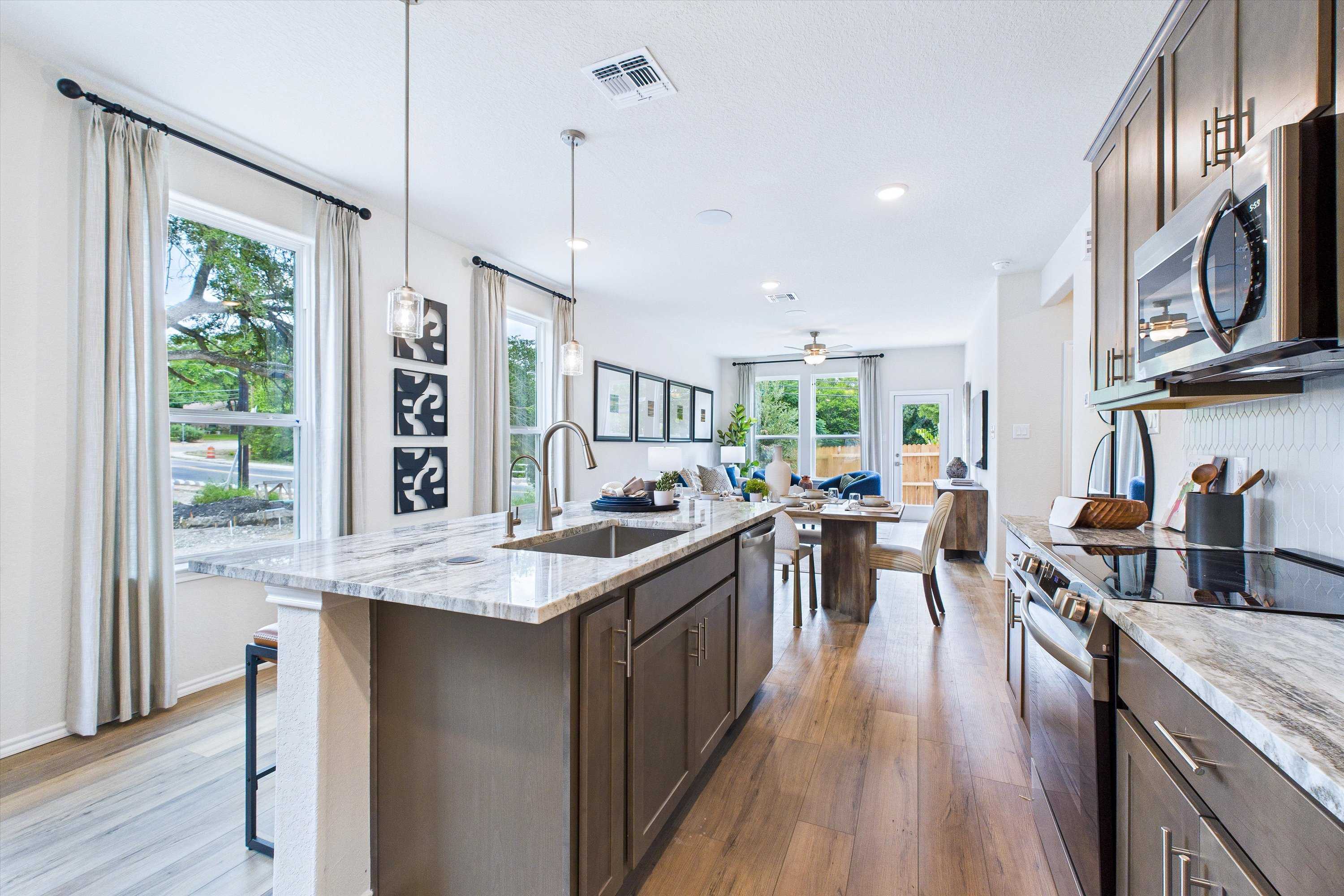 Spacious open-concept kitchen with marble island, hardwood floors, and dining area at Cedar Heights in San Antonio TX