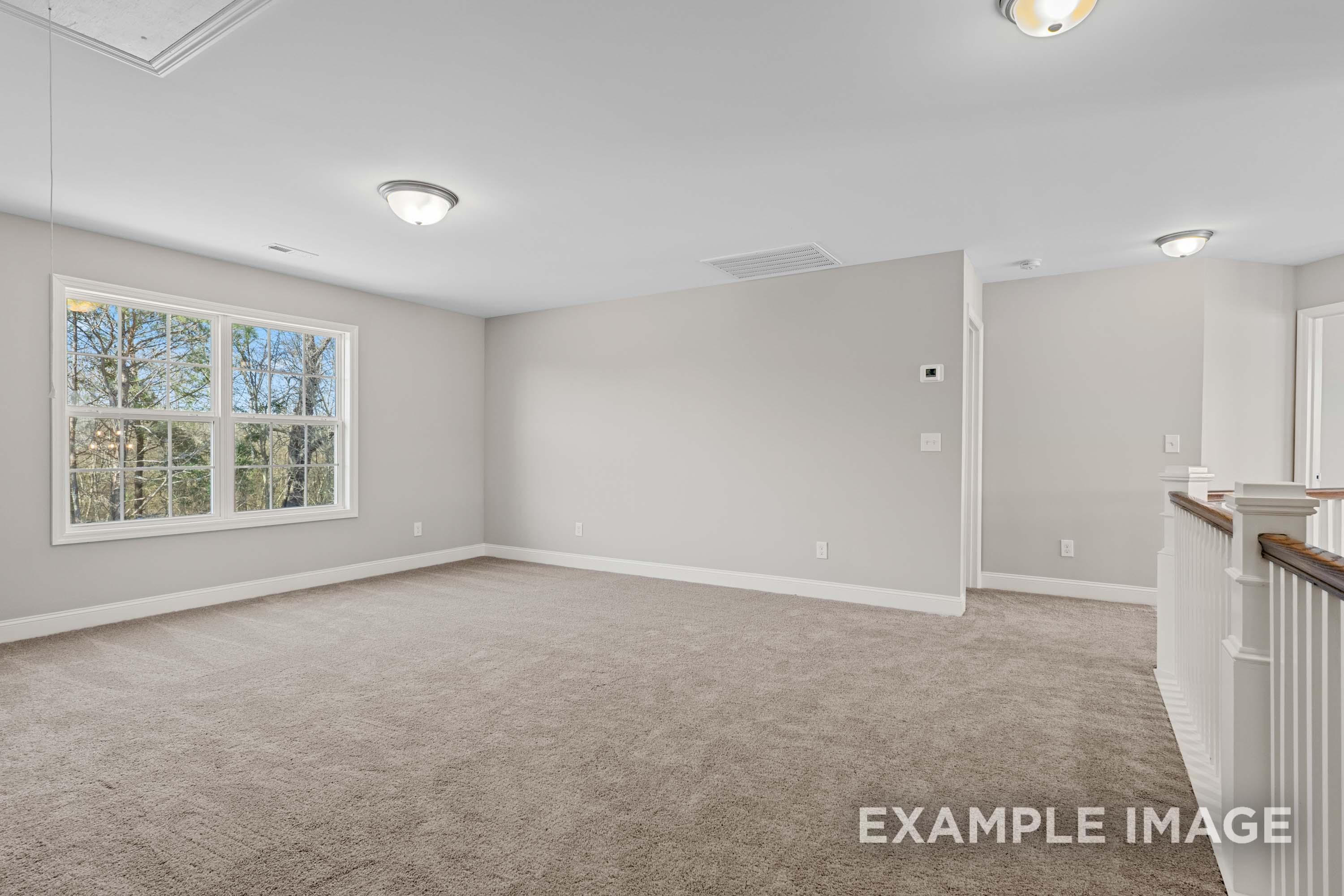 Spacious upper-floor loft in The Madison B with light gray walls, large tree-view windows, recessed lights, and open wooden railing
