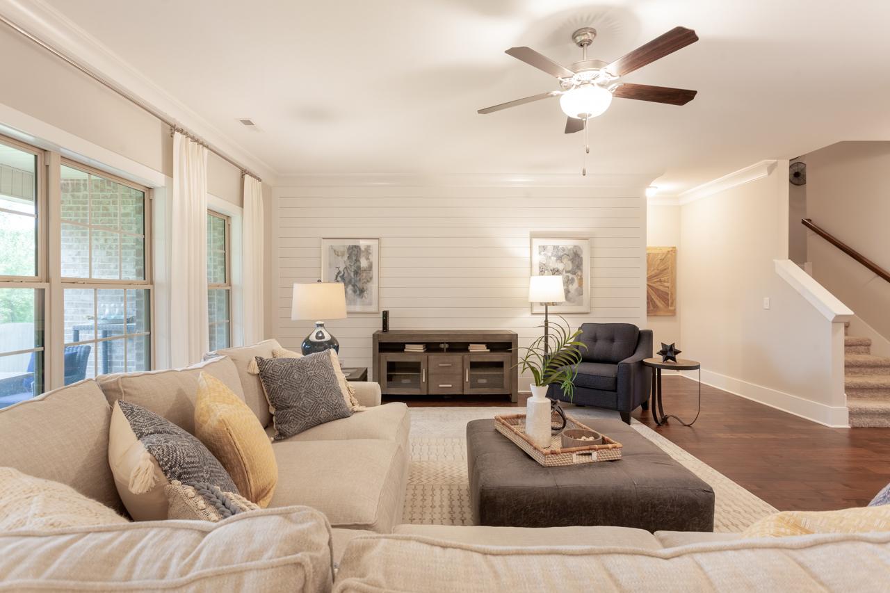 Spacious open-concept living room at Laurenwood Preserve in Madison AL with beige sofa, large windows, hardwood floors, and ceiling fan