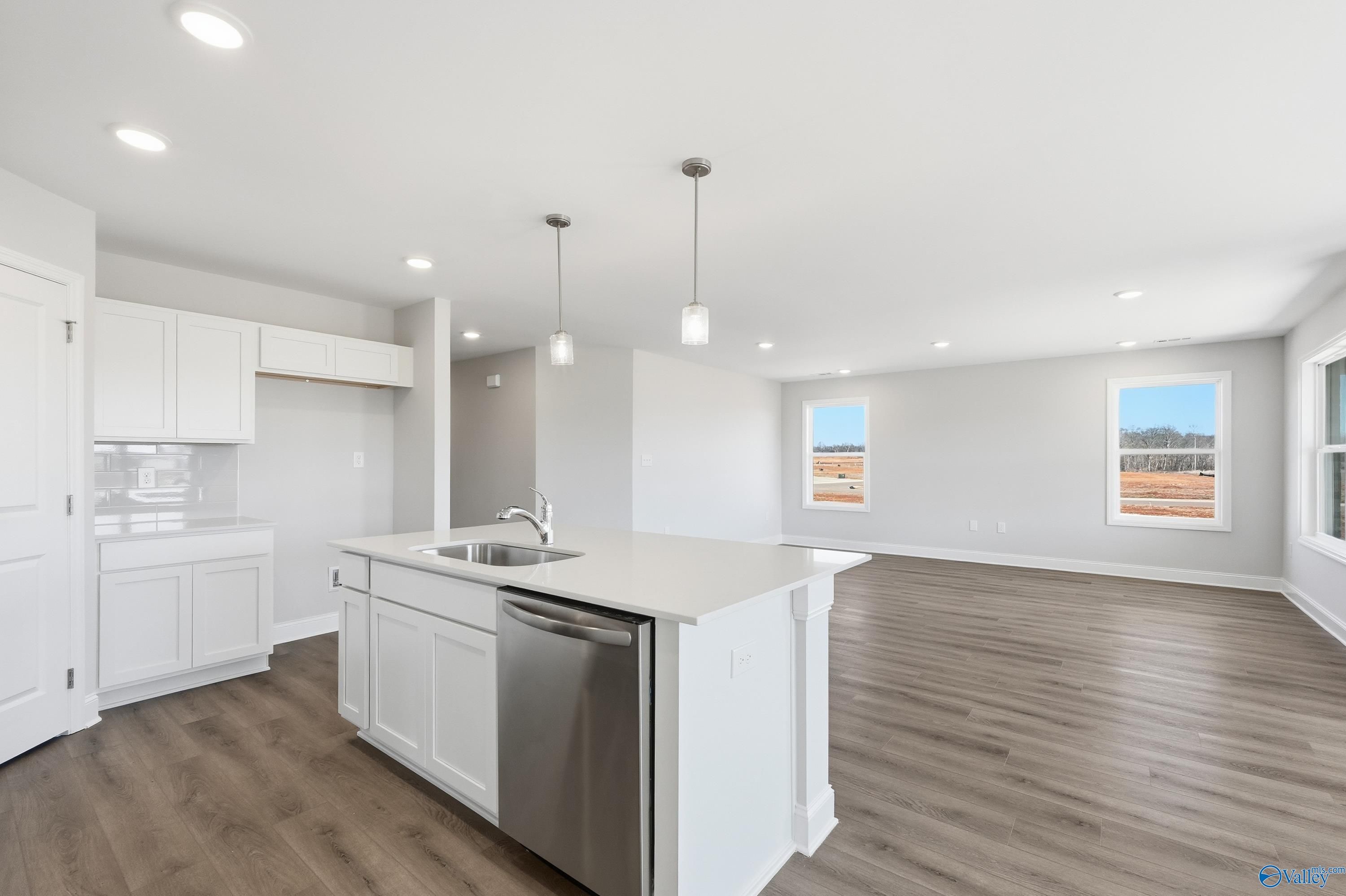 Open-concept kitchen with white cabinets, island sink, stainless dishwasher in Davidson Homes The Franklin, New Market, Alabama