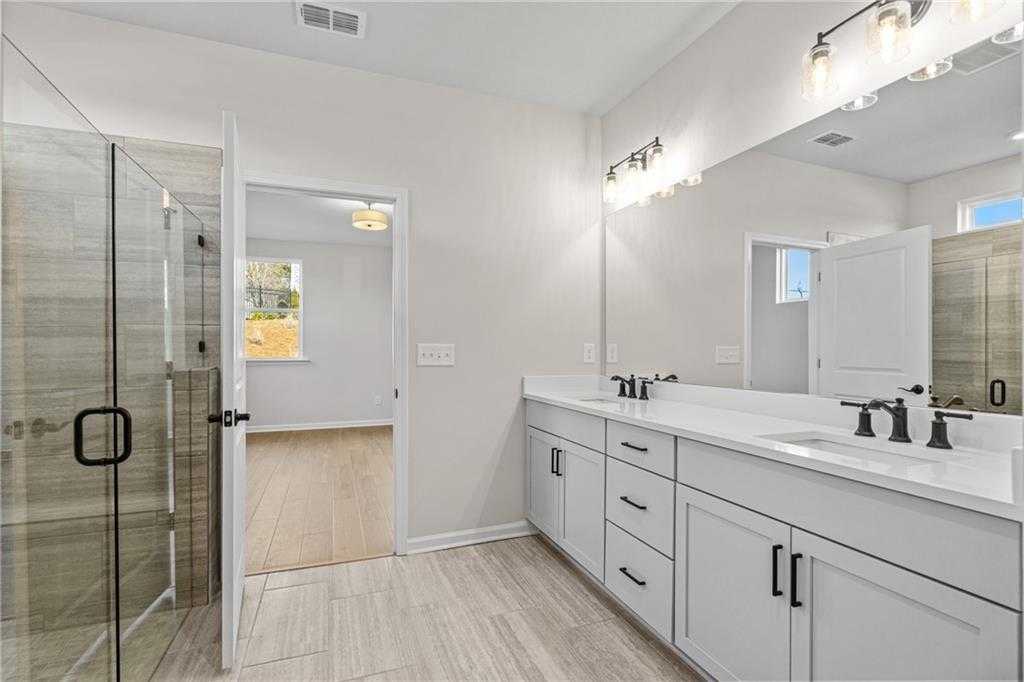 Modern master bathroom featuring frameless glass shower, double vanity, and quartz counters in Davidson Homes The Edison B, Loganville, GA