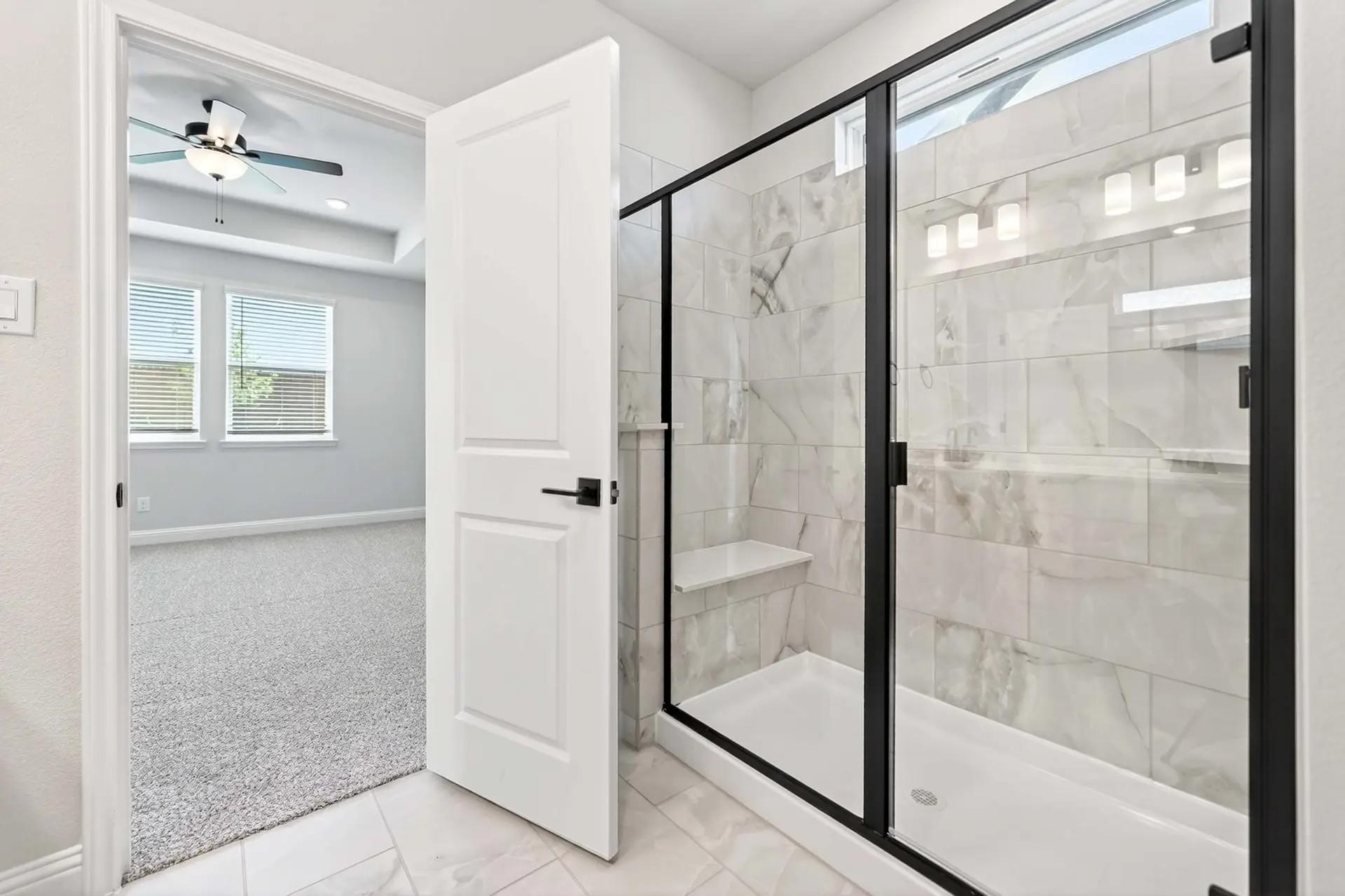 Modern walk-in tile shower with black frame in The Holly C floor plan by Davidson Homes in Heartland, Texas.