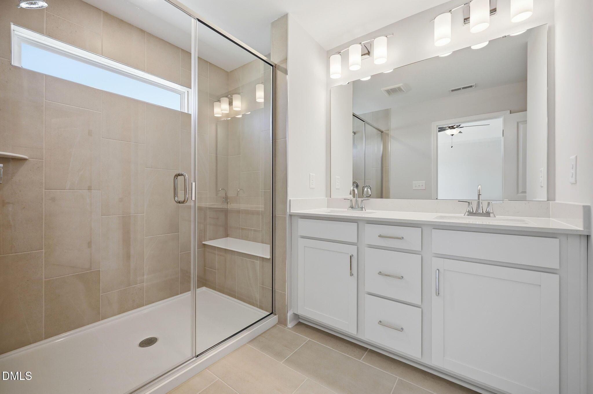Modern bathroom with double vanity and glass-enclosed walk-in shower in The Avery floor plan at Forestville Yard Townhomes.