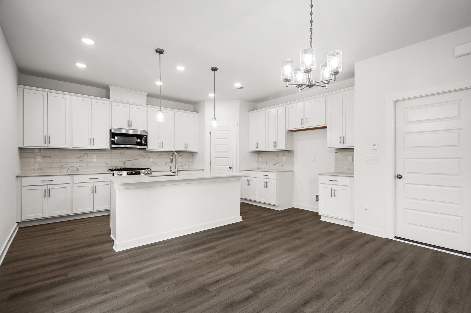 Modern kitchen with white cabinets, center island, and wood floors in The Logan C floor plan at Calista Farms, Tennessee.