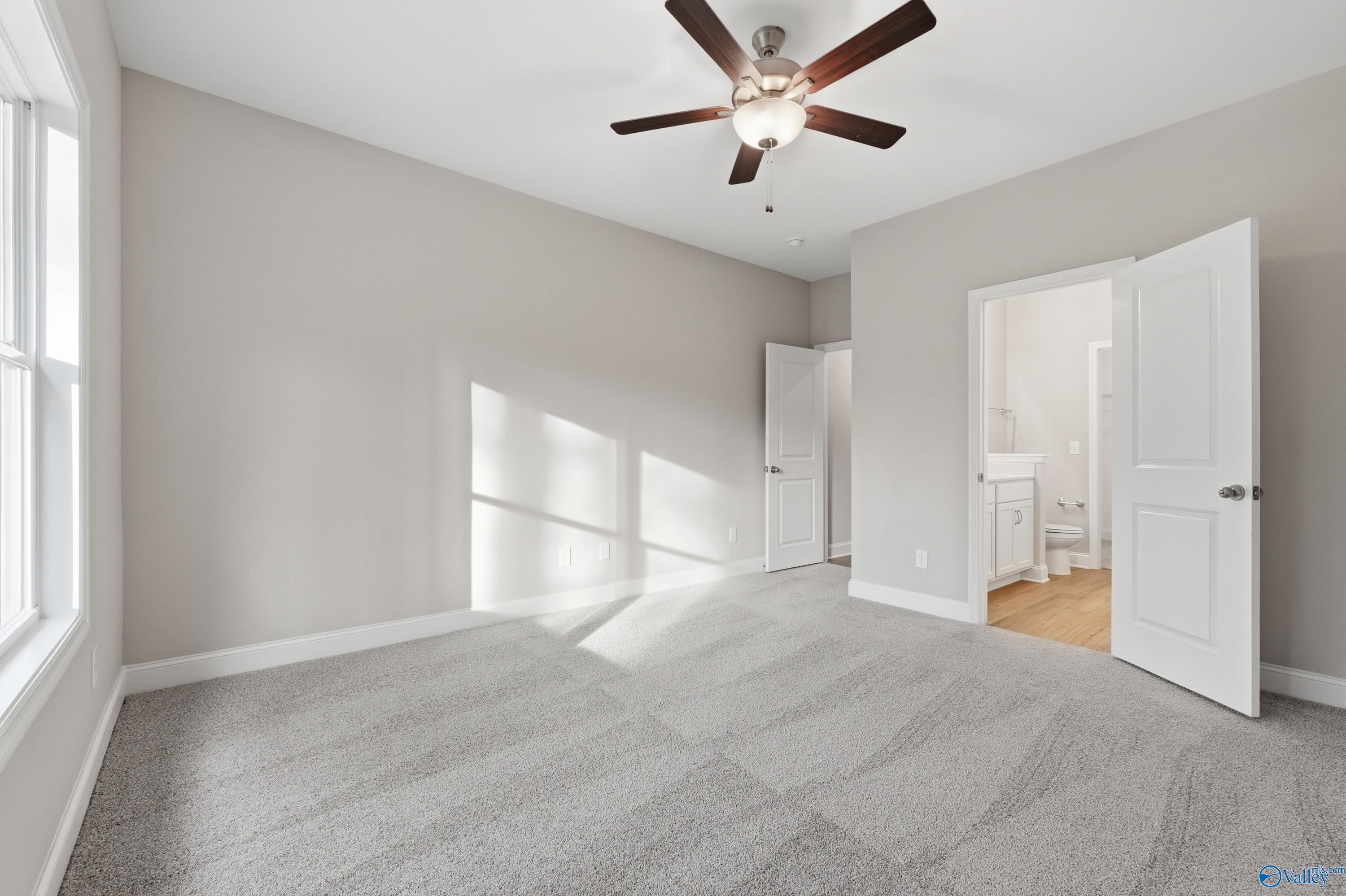 Bright bedroom with ceiling fan and open door to attached bathroom in Davidson Homes The Asheville, Arab, Alabama