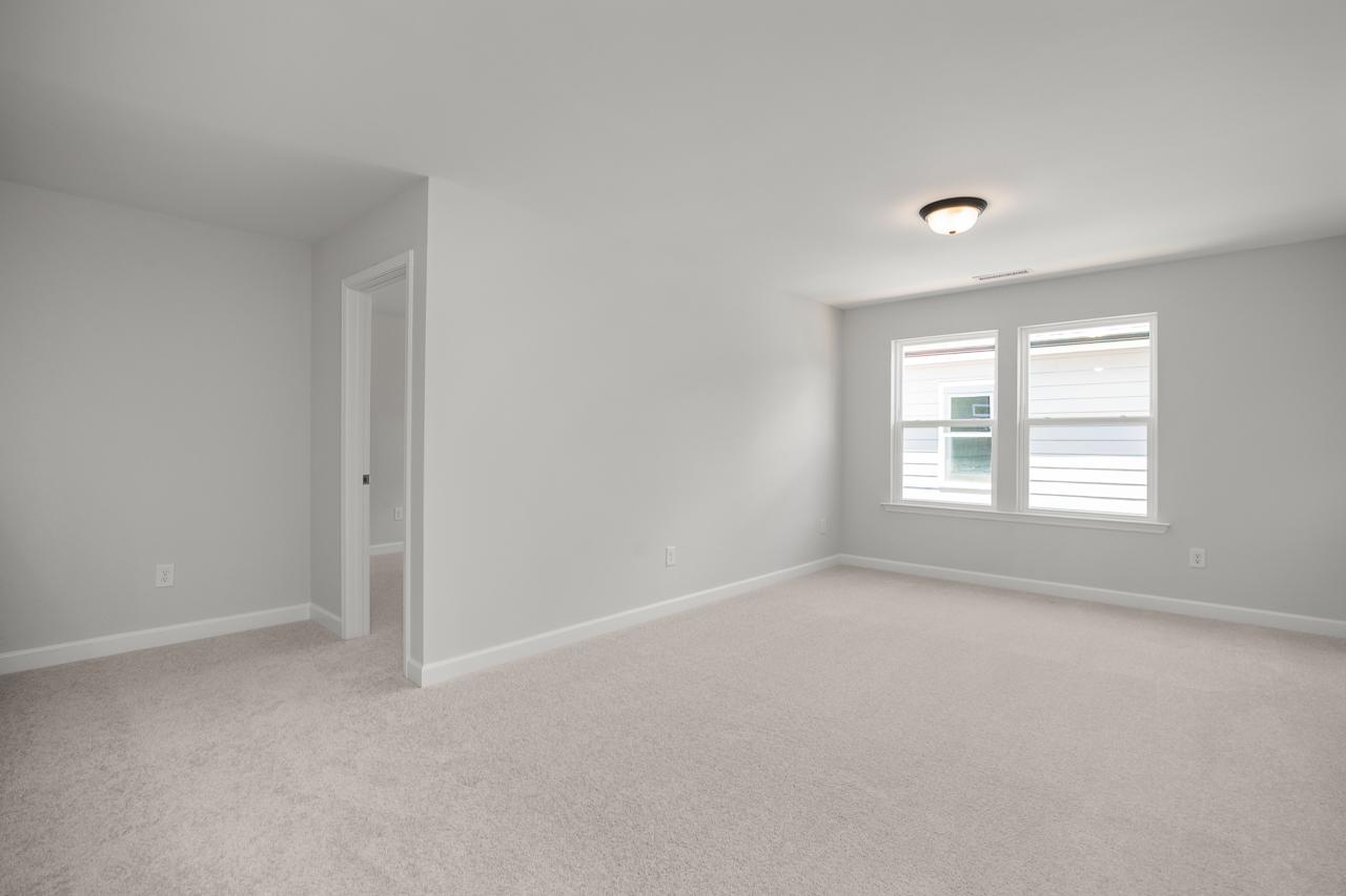 Spacious master bedroom in The Birch II D featuring neutral carpet, light walls, and natural light from large windows.