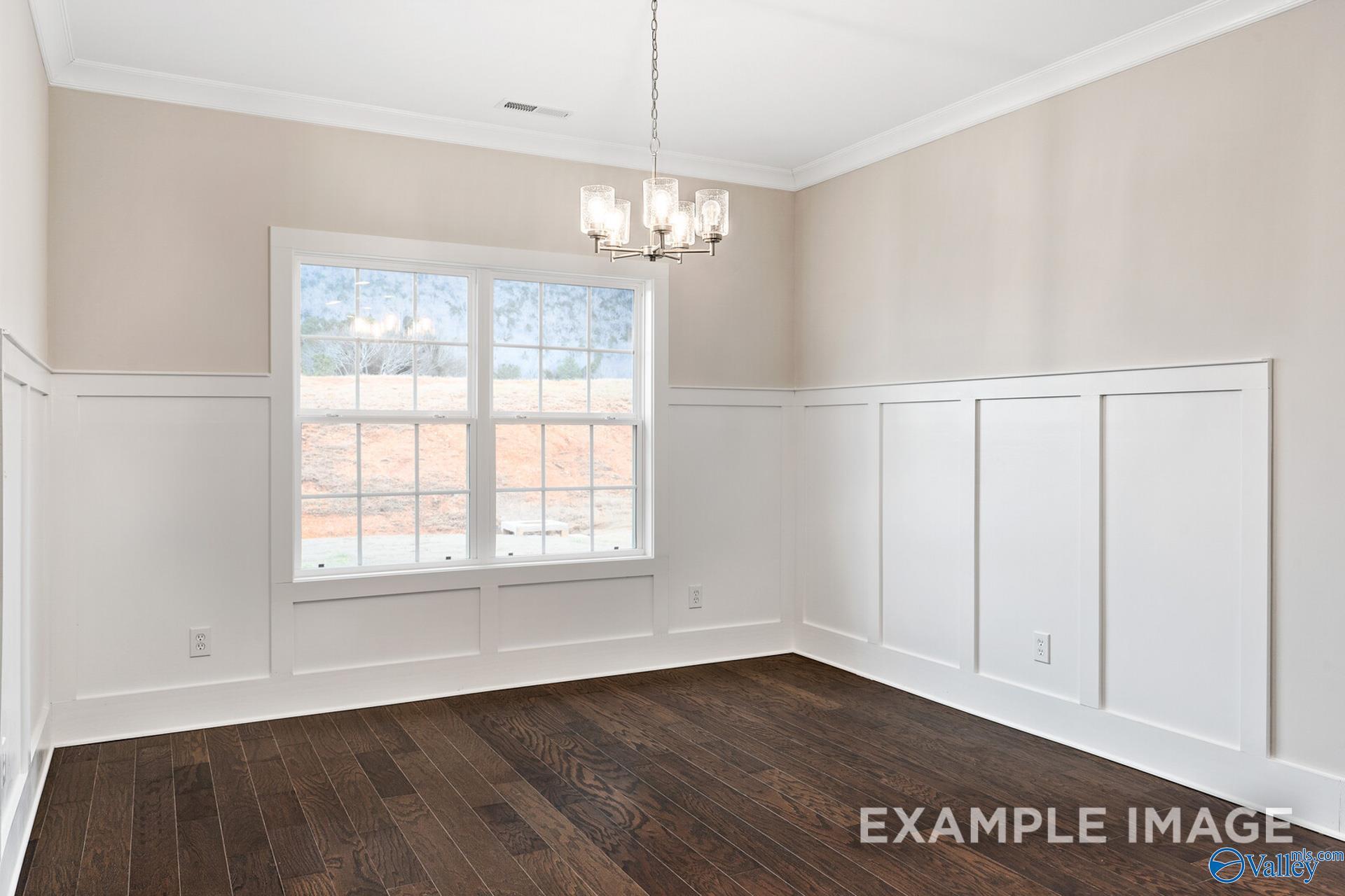 Bright dining room with white wainscoting, hardwood floors, chandelier, and large windows in Davidson Homes The Rockford, Harvest AL