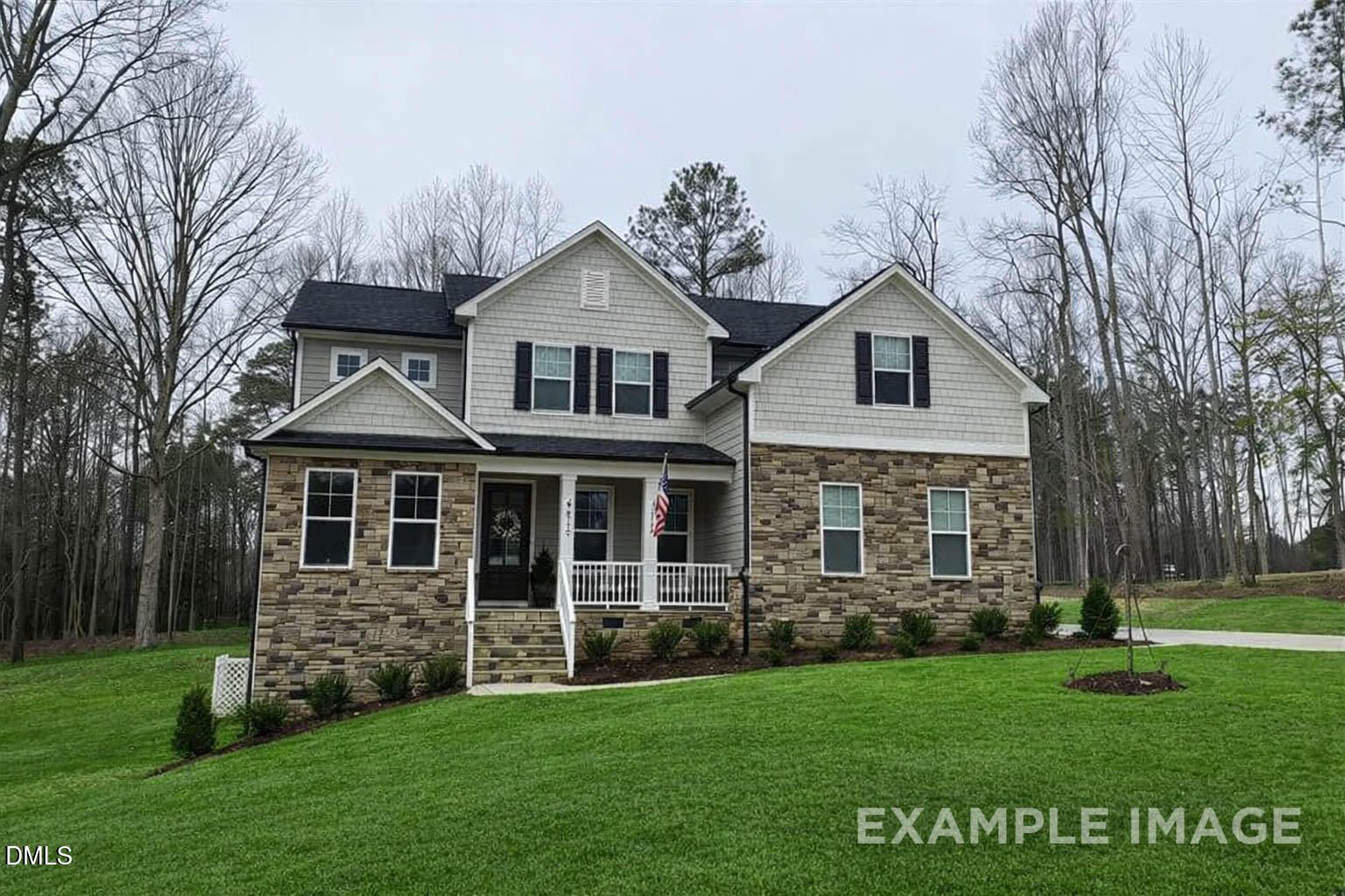 Two-story Crawford D home exterior with brick accents, front porch, and American flag in Laneridge Estates, Raleigh, NC