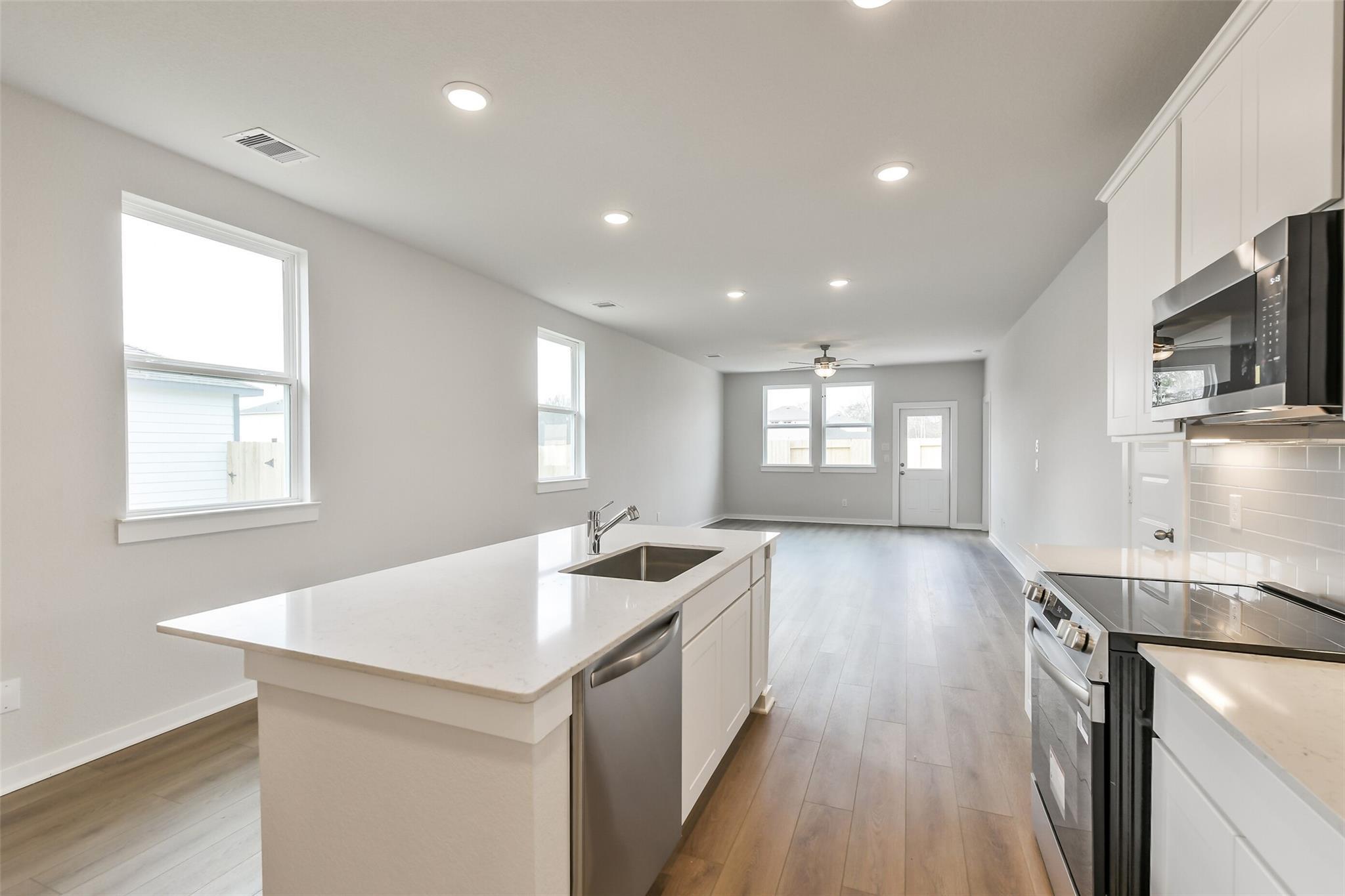 Modern open kitchen with white quartz island, stainless steel appliances in The Frio G 3-bedroom home, Cleveland, Texas