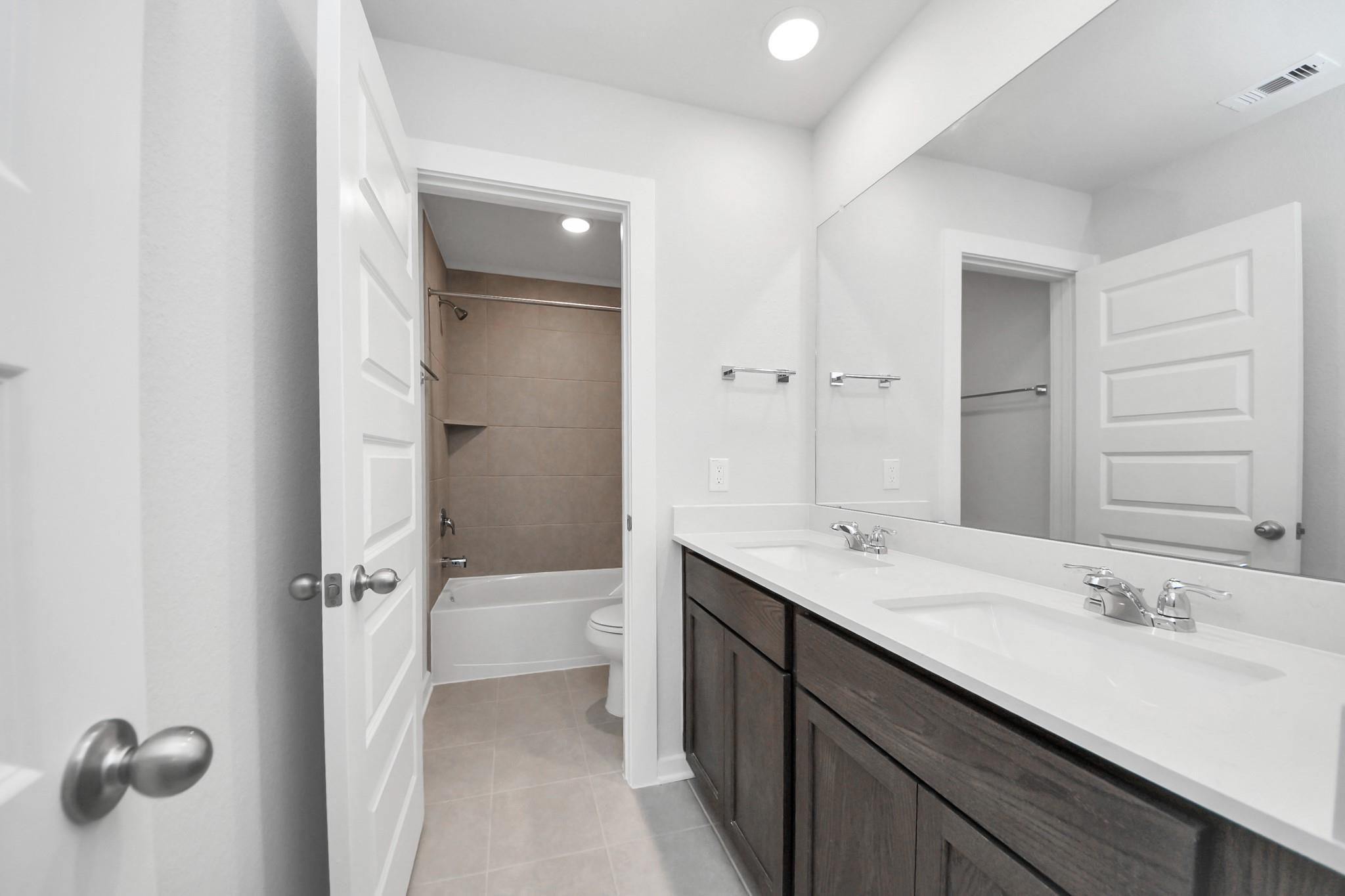 Modern bathroom with dual-sink vanity and shower-tub combo in The Brazos F floor plan, Liberty Estates, Cleveland, Texas.