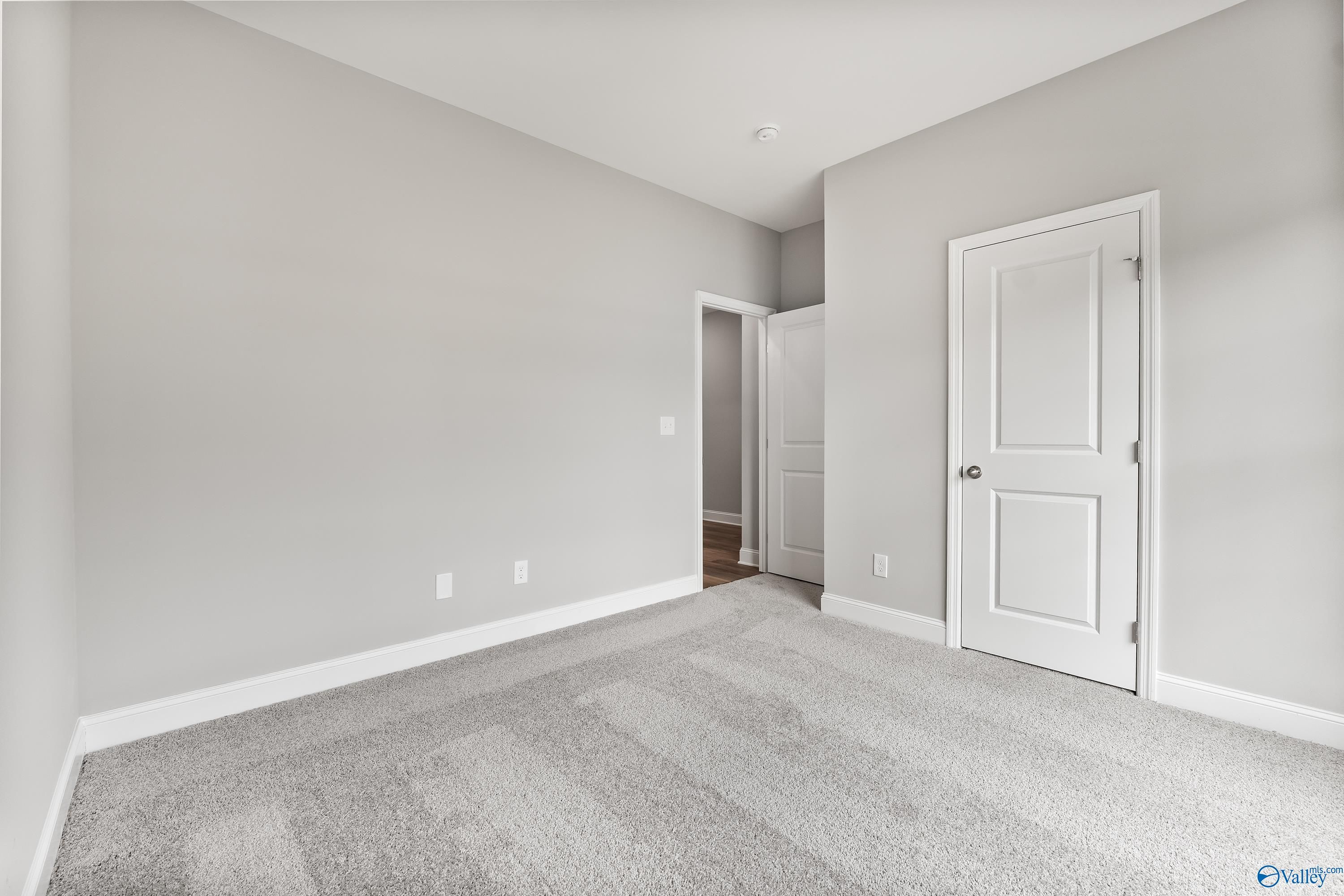 Empty secondary bedroom featuring light gray walls, white doors, and plush carpet in Davidson Homes The Franklin C, Huntsville, Alabama
