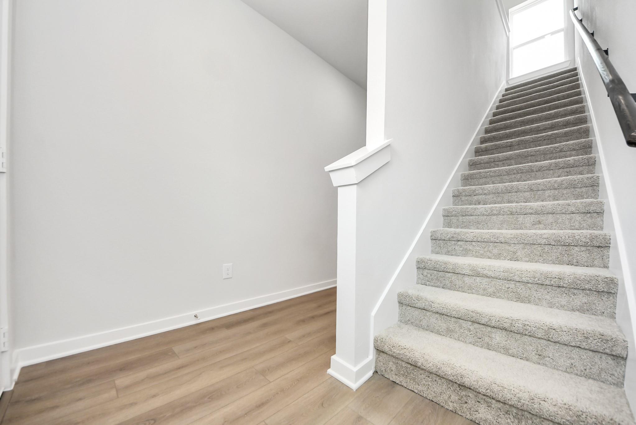 Carpeted staircase with white railing in The Blanco E floor plan at The Villages at WestPointe in Dayton, Texas.