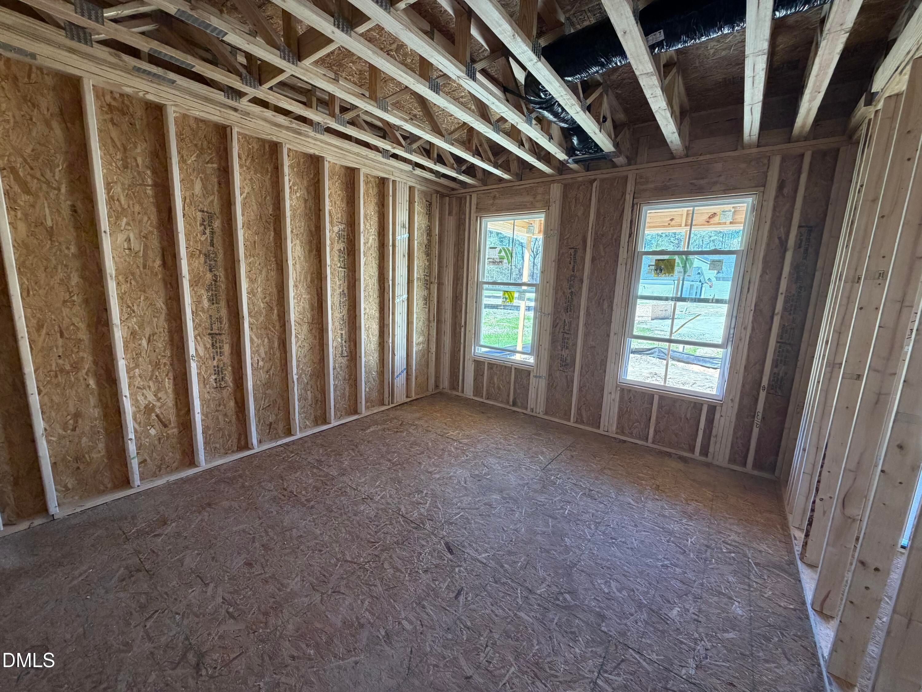 Spacious unfinished room with wooden framing, plywood walls, and large windows in The Hickory II B by Davidson Homes, Lillington, NC