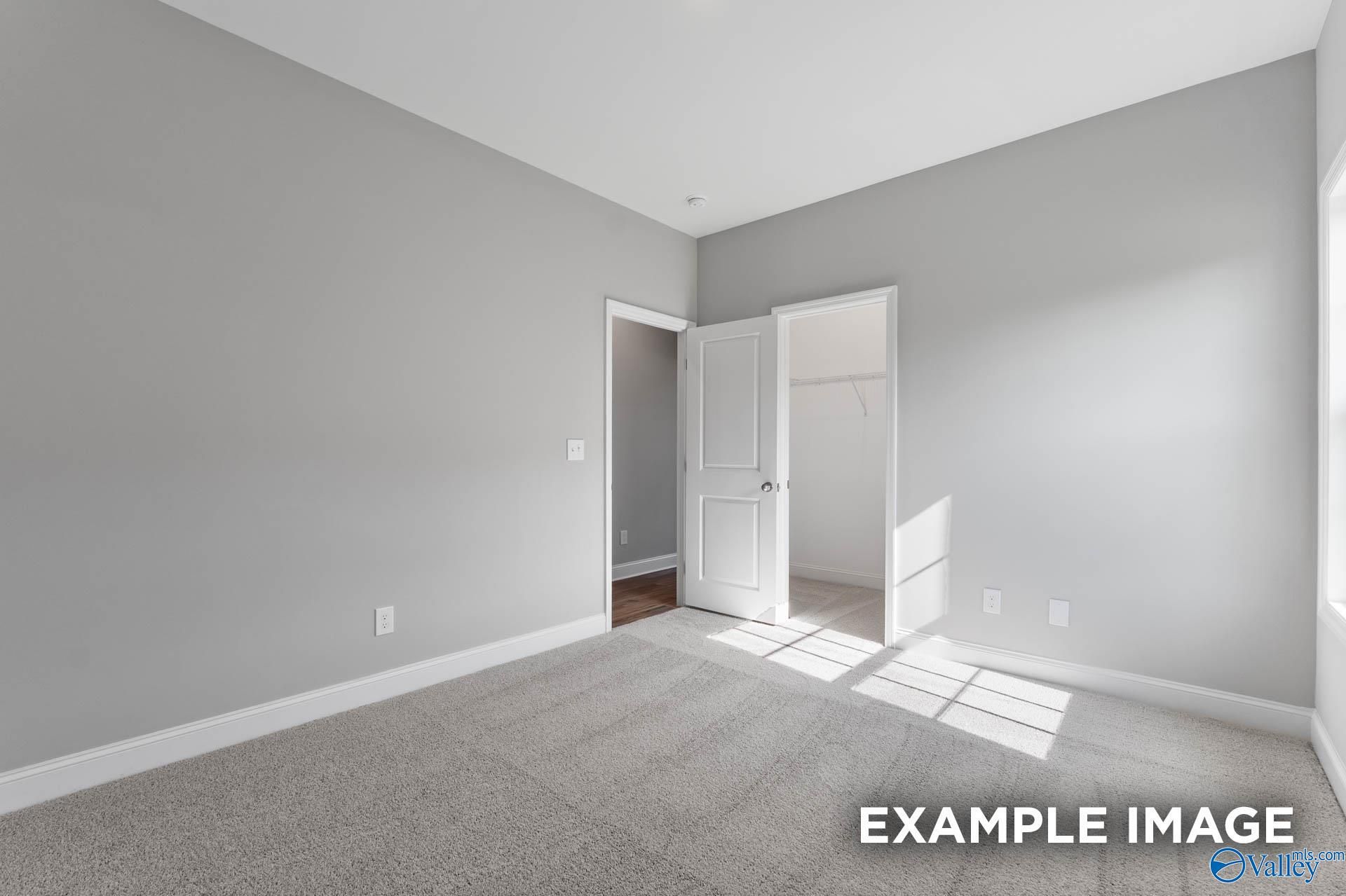 Bright bedroom with gray walls, open closet door, carpet flooring, and natural light in Davidson Homes The Rockford D, Hazel Green, Alabama