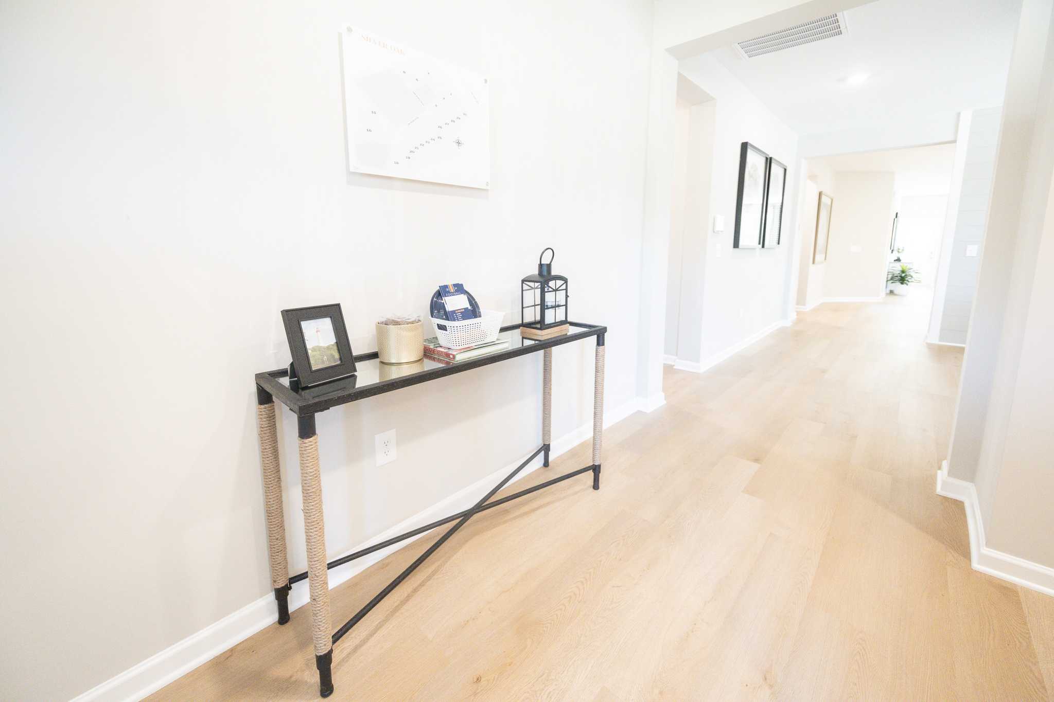 Spacious entry hallway in Silver Oak Cusseta Alabama with light oak floors black rattan console table blue lantern and arched doorways