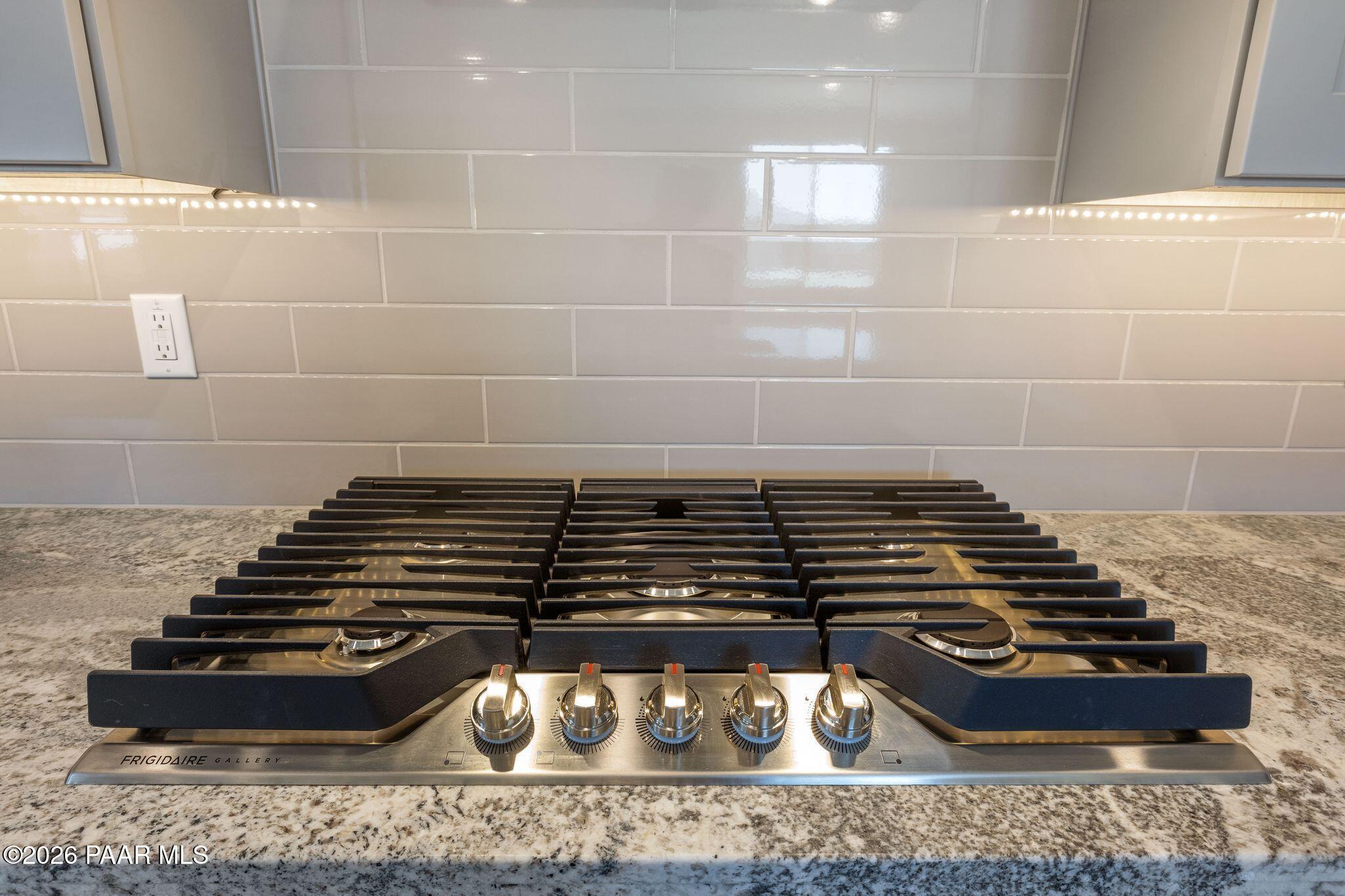 Modern gas cooktop with five stainless burners on granite countertop in Davidson Homes The Frontier A kitchen, Prescott Valley, AZ