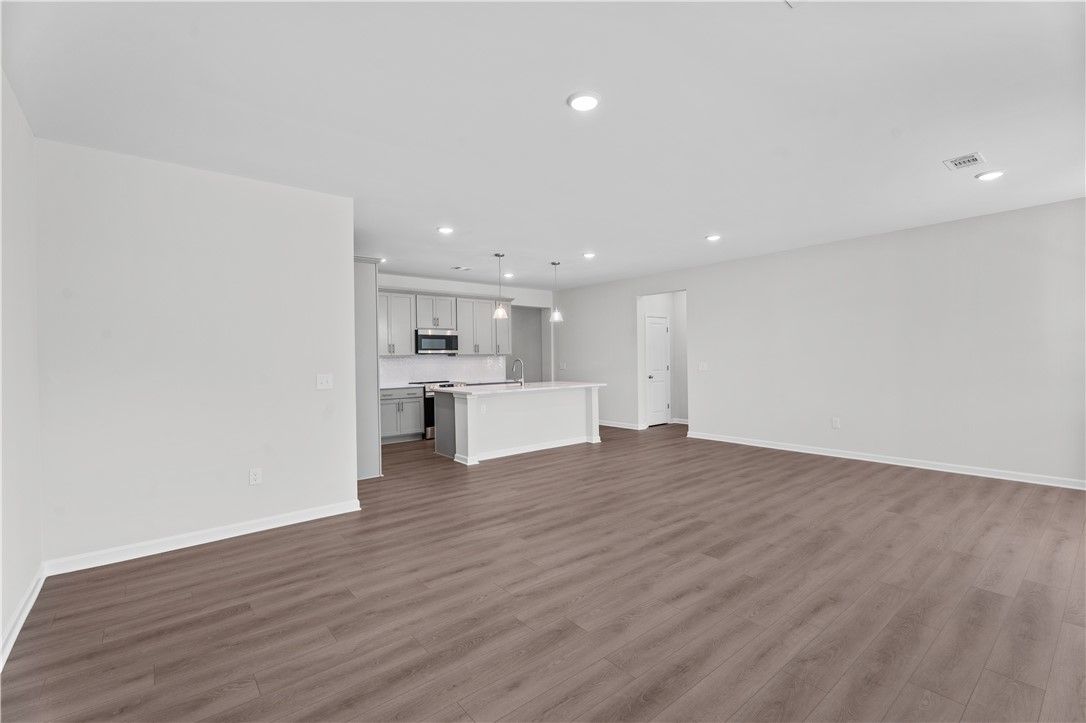 Modern open kitchen with white cabinets, stainless appliances, and large island in The Luna B, Davidson Homes, Opelika AL