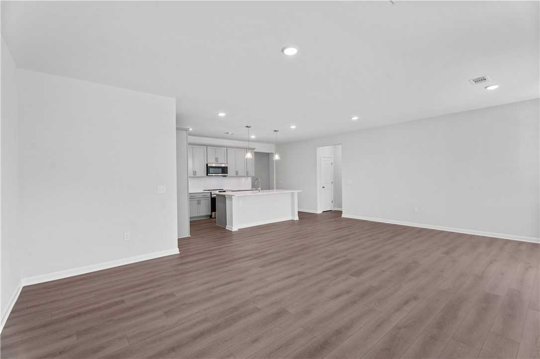 Modern open kitchen with white cabinets, stainless appliances, and large island in The Luna B, Davidson Homes, Opelika AL