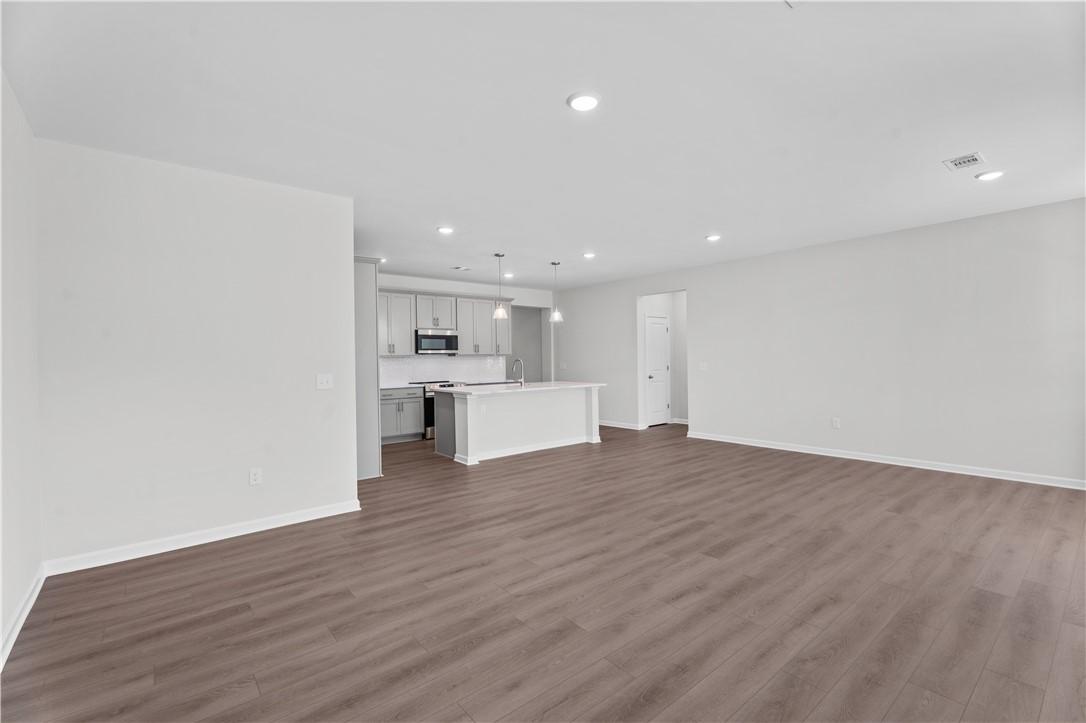 Modern open kitchen with white cabinets, stainless appliances, and large island in The Luna B, Davidson Homes, Opelika AL