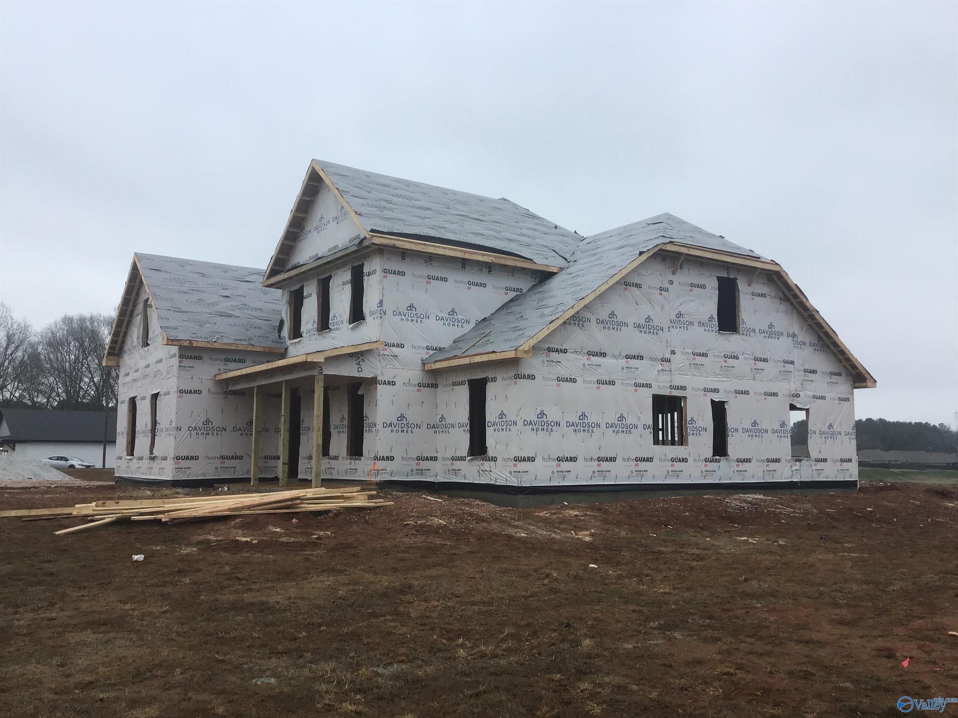 Two-story framed home under construction with shingled roof and house wrap in Hollon Meadow, Decatur, Alabama