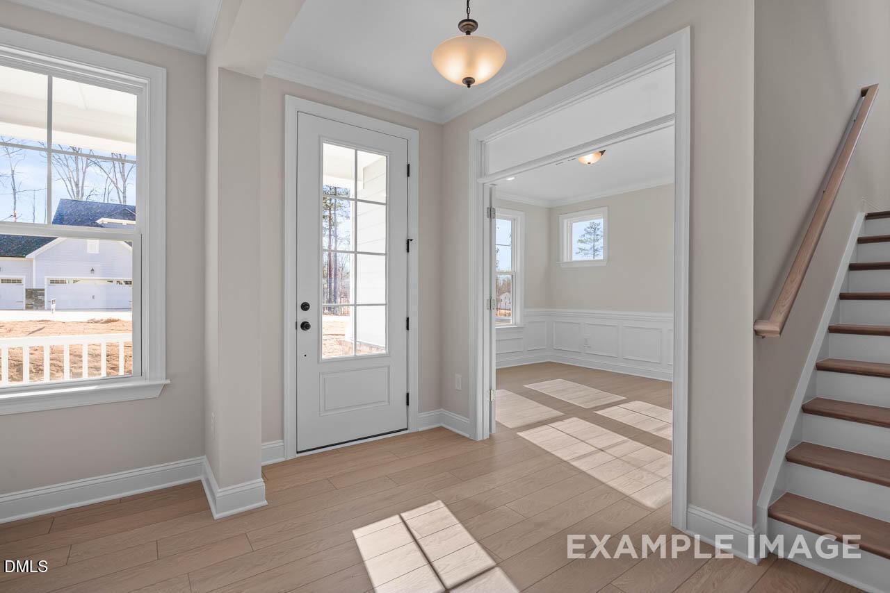 Bright entry foyer with hardwood floors, glass-front door, chandelier, and staircase in Davidson Homes The Crawford D, Angier, NC