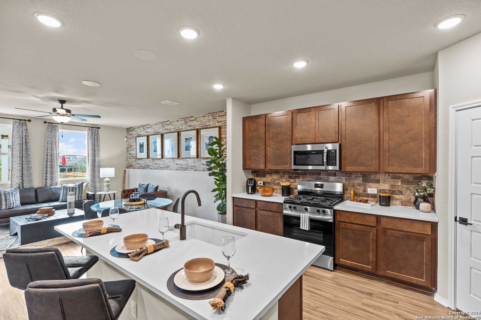 Modern open-concept kitchen with stainless appliances, wooden cabinets, and island bar in Davidson Homes The Douglas F, San Antonio