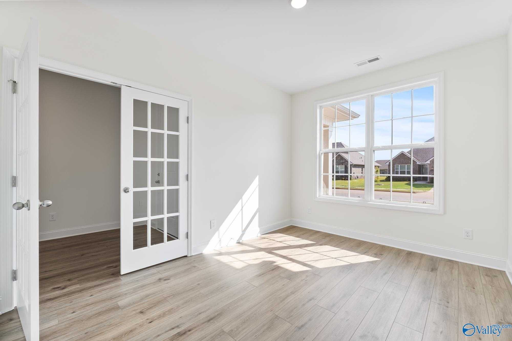 Bright study room with French doors, hardwood floors, and sunny windows overlooking neighborhood in Davidson Homes The Harrison, Meridianville, AL