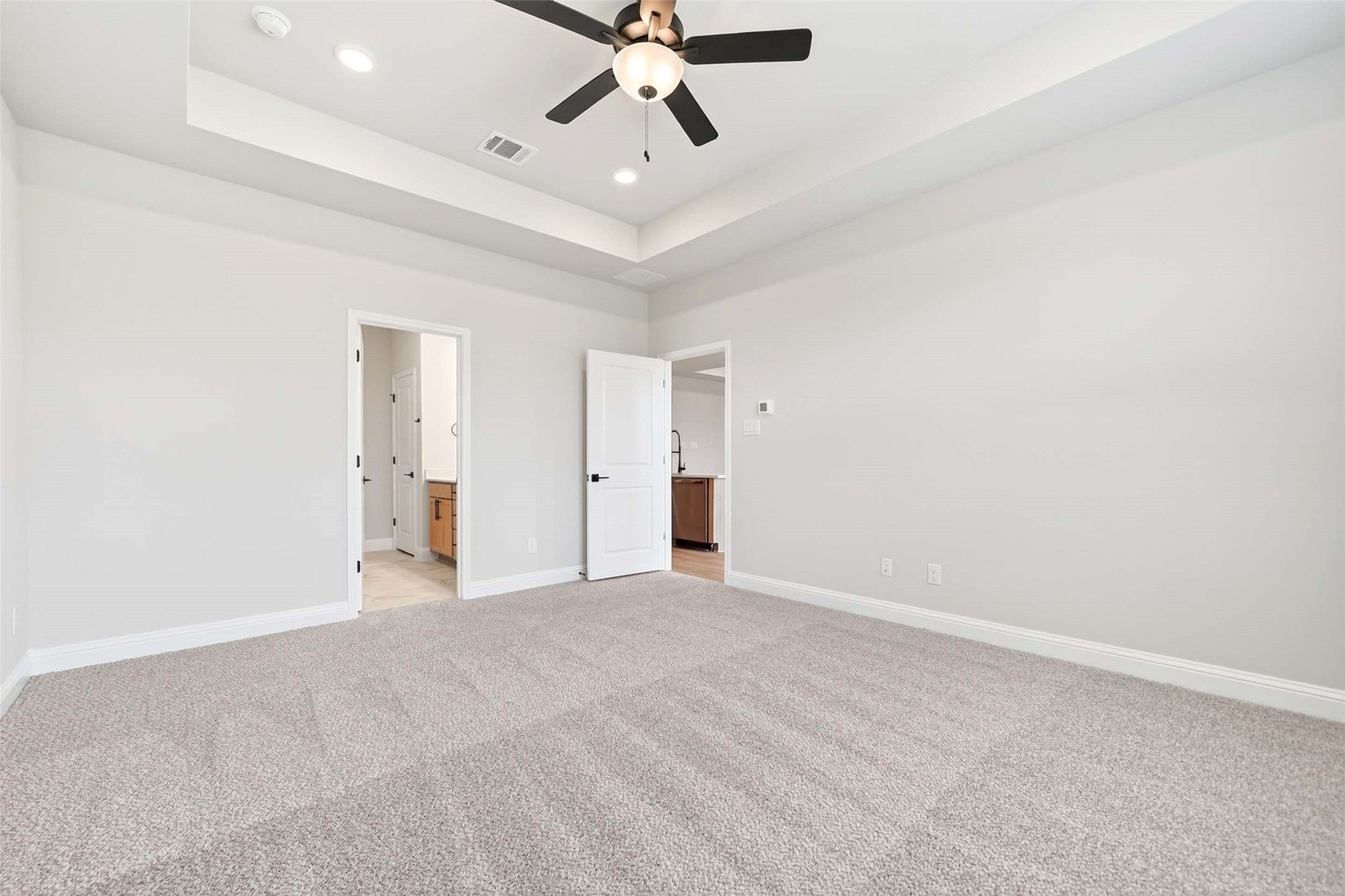Spacious bedroom with tray ceiling and ceiling fan in Davidson Homes The Holly C plan, Parks at Foster Crossing, Anna, TX.