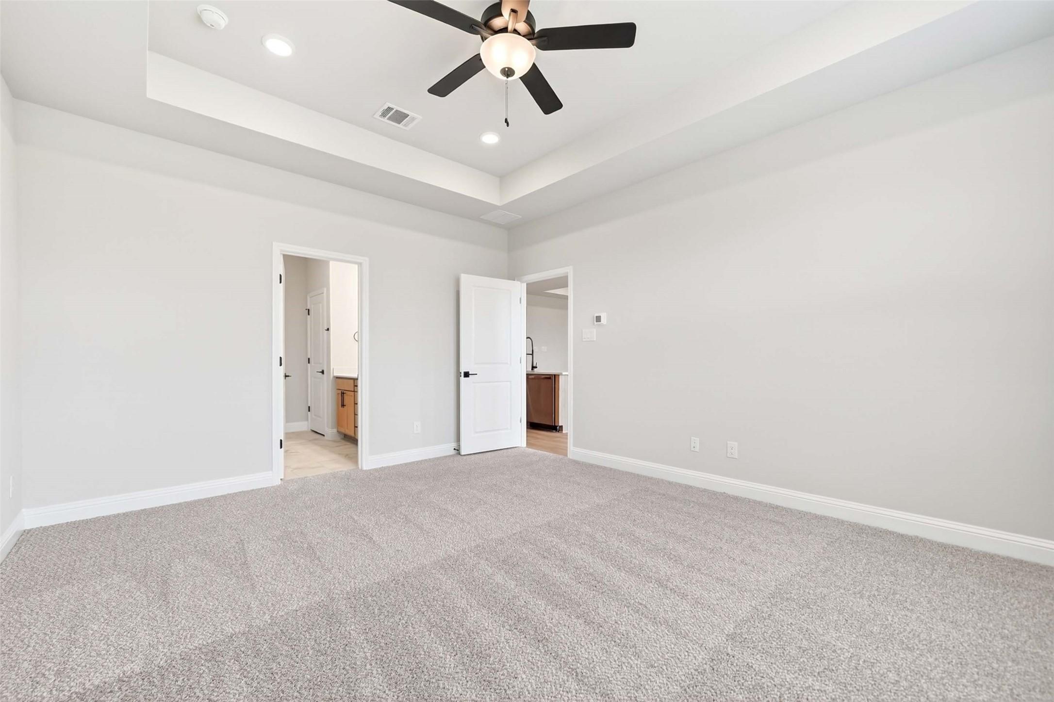 Spacious bedroom with tray ceiling and ceiling fan in Davidson Homes The Holly C plan, Parks at Foster Crossing, Anna, TX.