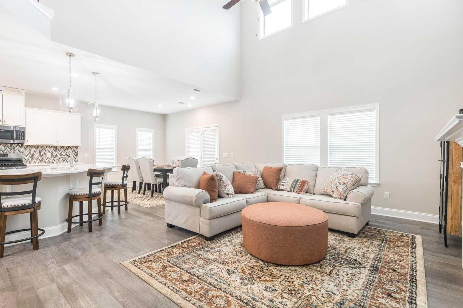 Spacious open-concept kitchen and living room at Links Crossing in Auburn Alabama with island bar hardwood floors fireplace and beige sofa