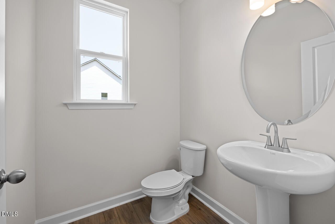 Modern half bathroom with pedestal sink and round mirror in The Hickory II B floor plan at Montrose, Aberdeen, NC.