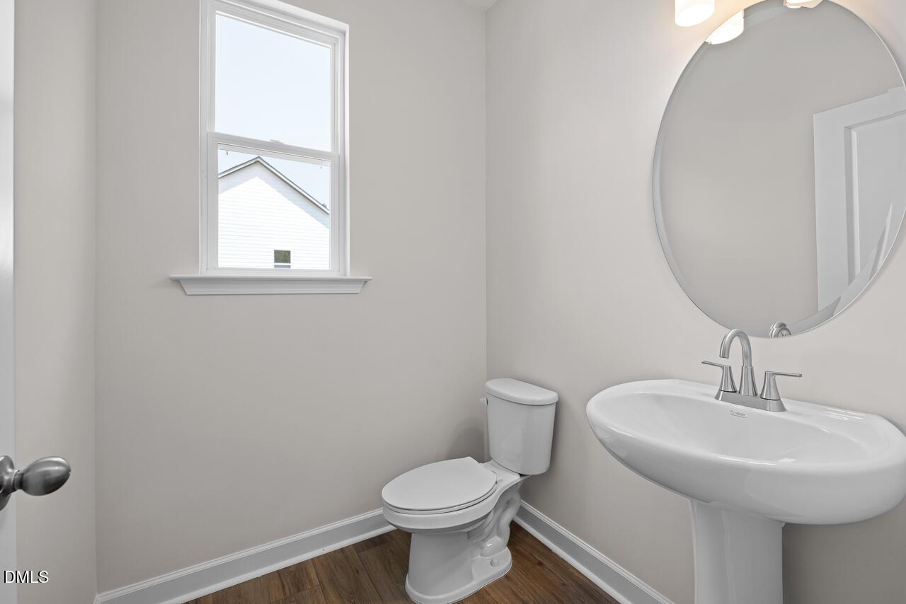 Modern half bathroom with pedestal sink and round mirror in The Hickory II B floor plan at Montrose, Aberdeen, NC.
