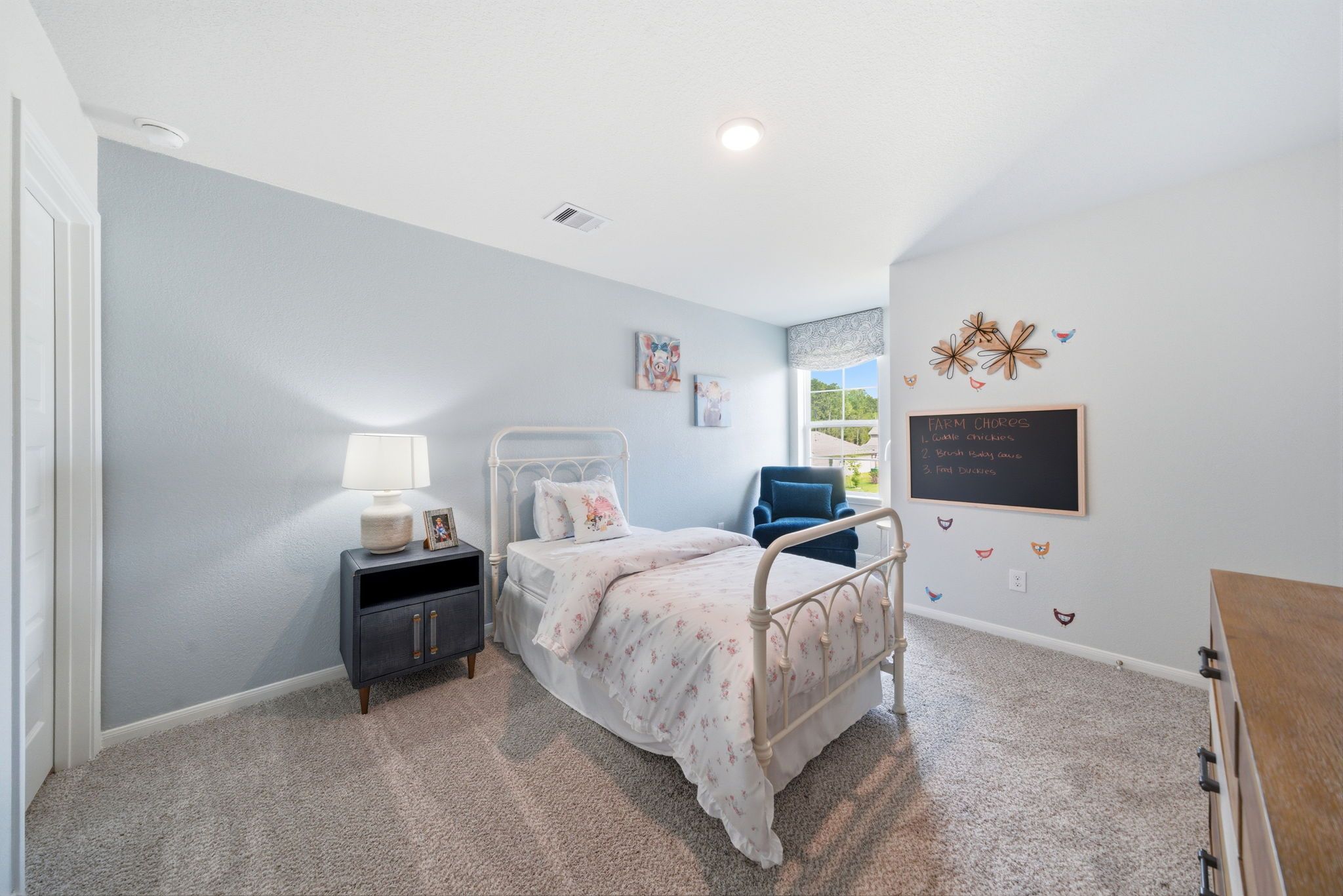 Cozy girl's bedroom at Liberty Estates in Cleveland, Texas by Davidson Homes with white metal bed, pink bedding, and chalkboard wall