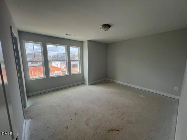 Spacious empty upstairs bedroom with light gray walls, three large windows overlooking construction, and ceiling fan in The Adalynn B, Lillington, NC