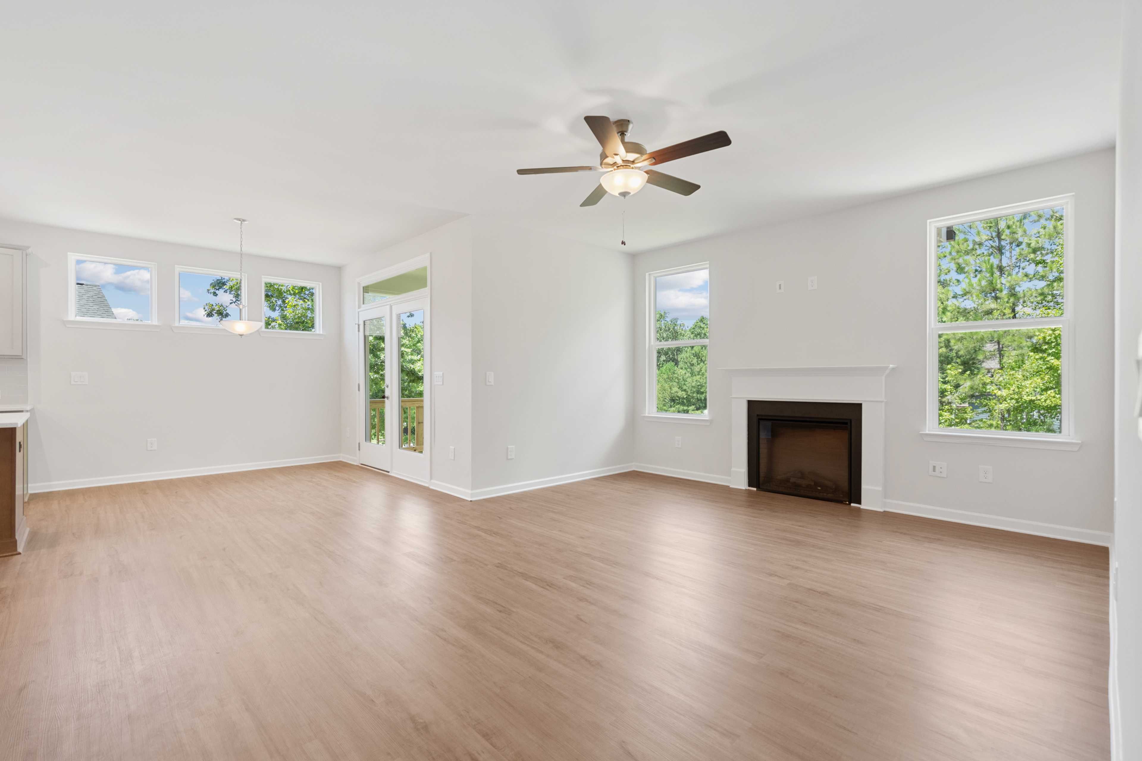 Spacious open-concept living room at Mountainbrook in Cartersville GA with hardwood floors, fireplace, French doors, and large windows
