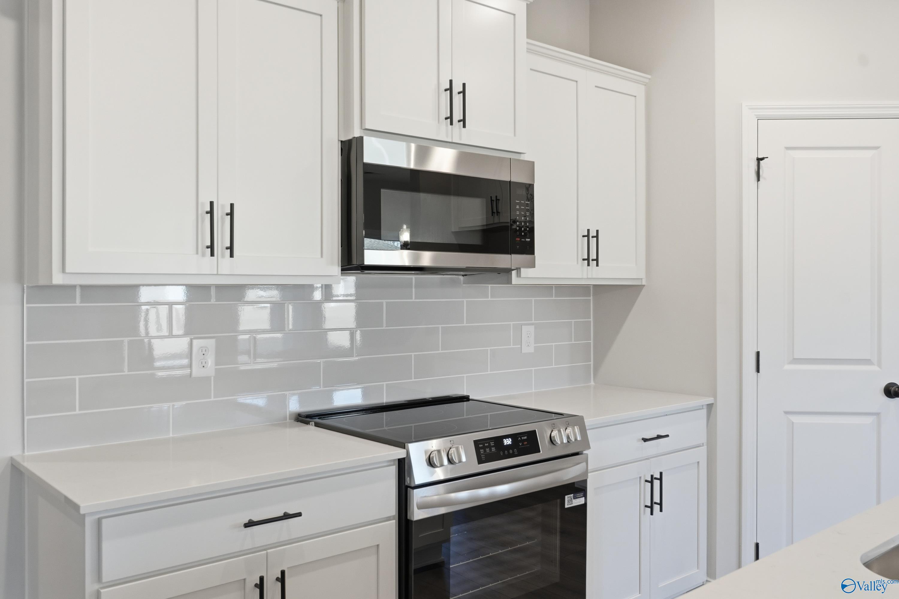 Modern white kitchen with stainless steel appliances, subway tile backsplash in Davidson Homes The Daphne D, Arab, Alabama