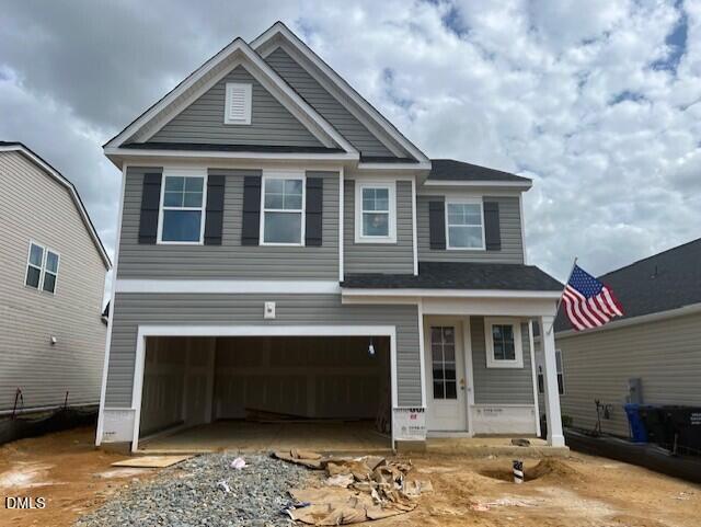 Two-story gray home with two-car garage and American flag in Gregory Village, Lillington, NC - Davidson Homes Adalynn A