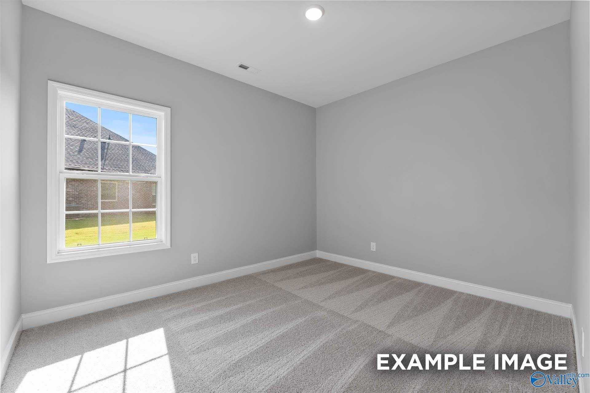 Bright secondary bedroom with gray walls, large sunny window overlooking yard, carpet floor in Davidson Homes Rockford D, Hazel Green AL