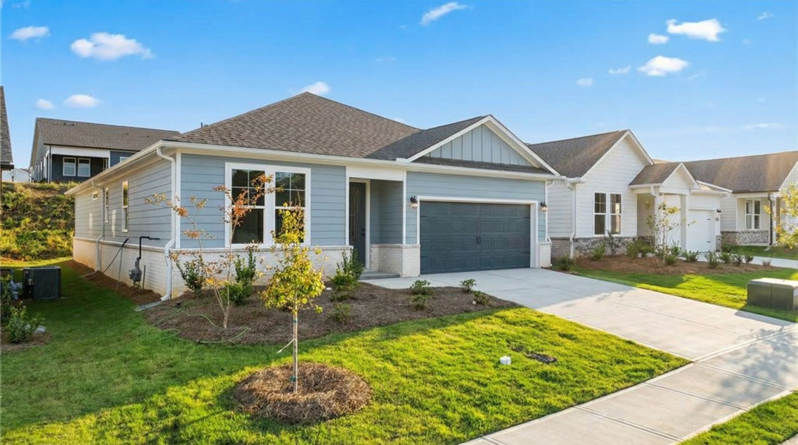 Light blue single-story 3-bedroom home with 2-car garage, driveway, and landscaped yard in Kelly Preserve, Loganville, Georgia