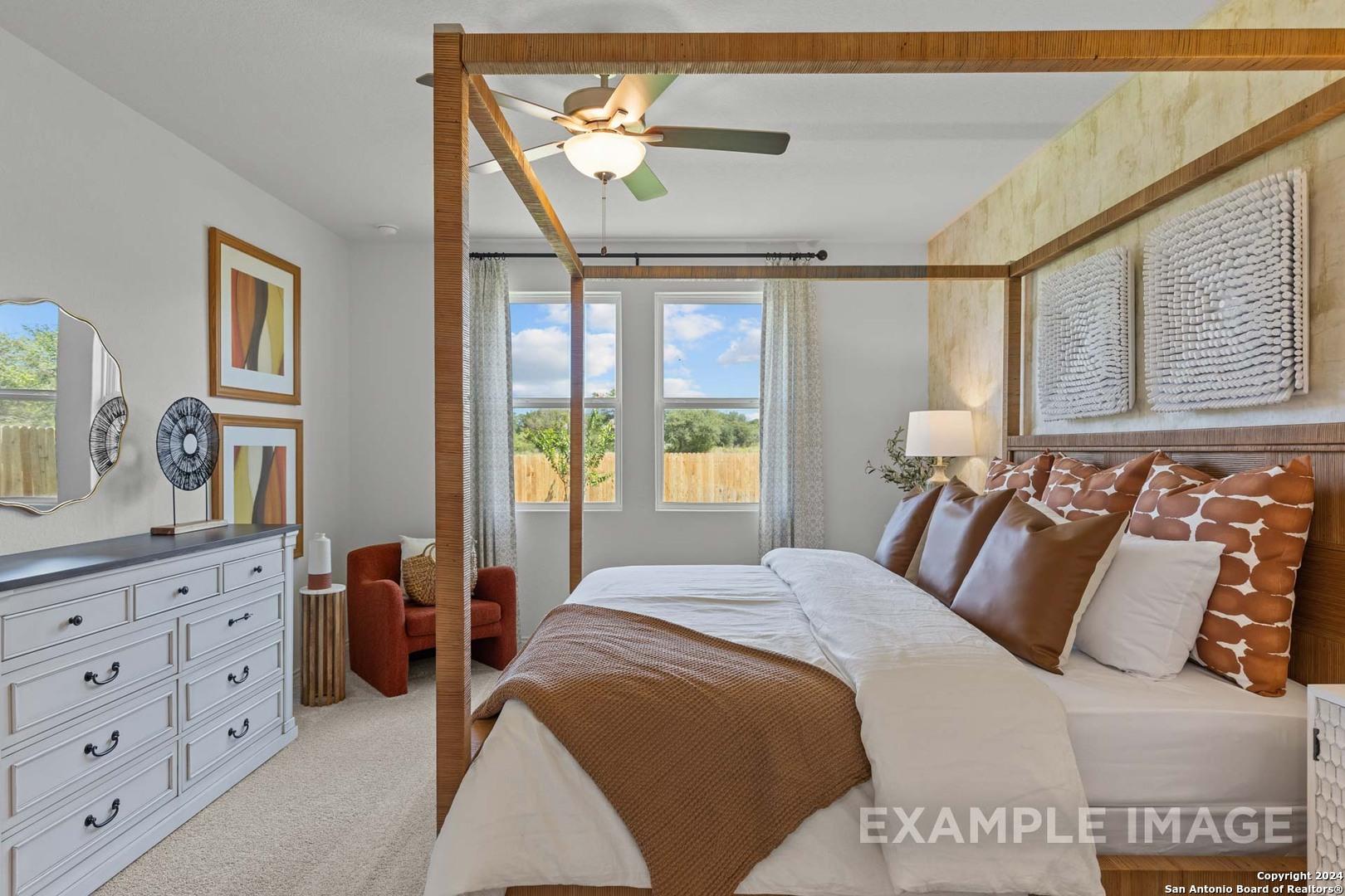 Elegant master bedroom with wooden canopy king bed, ceiling fan, and garden-view windows in Davidson Homes The Daphne K, San Antonio