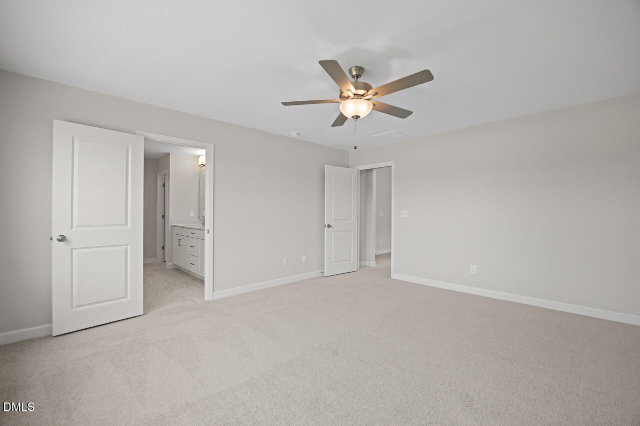 Spacious bedroom with ceiling fan and attached bathroom in The Chestnut floor plan at Wendell Ridge, Wendell, North Carolina.