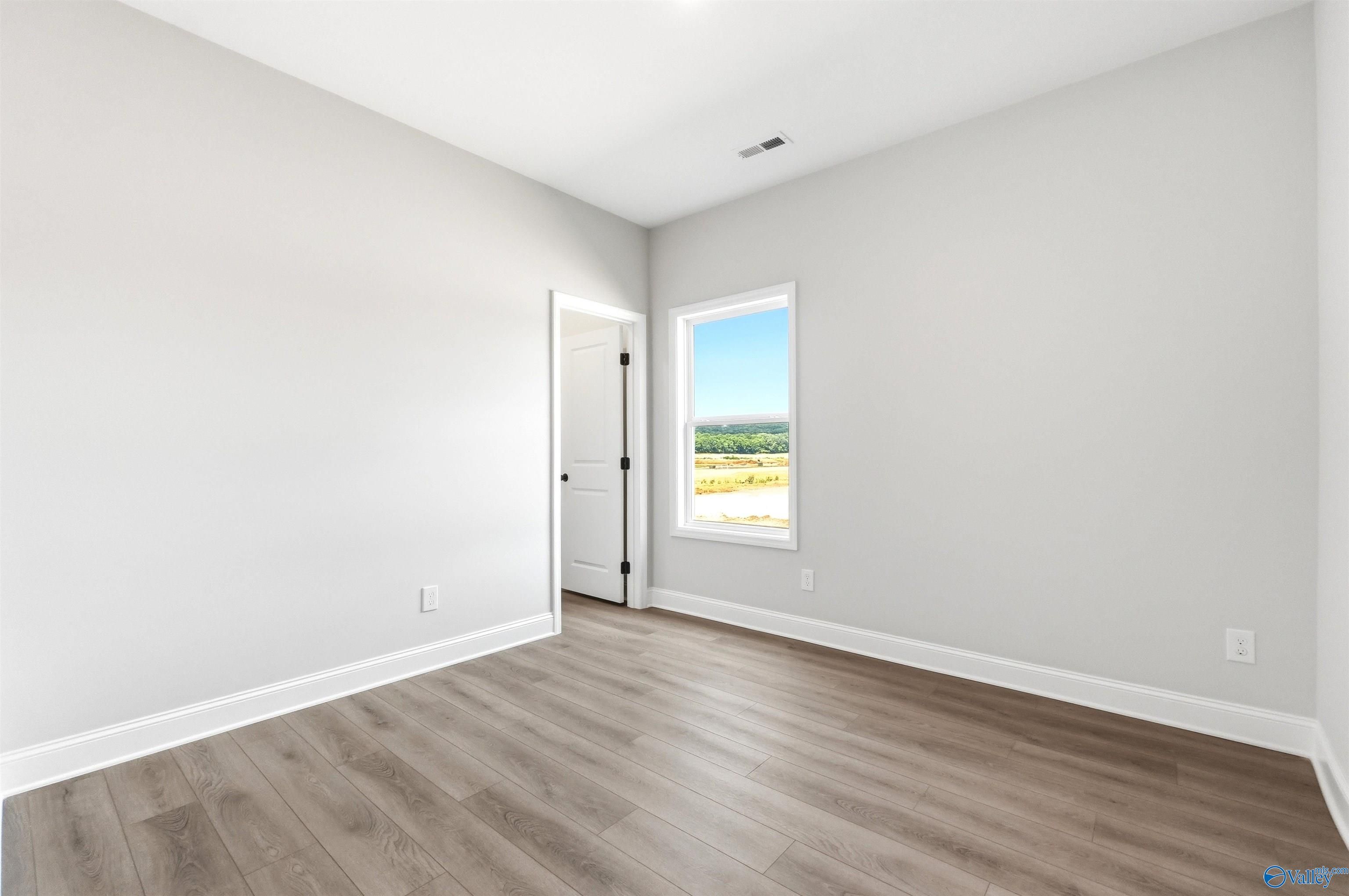 Bright, neutral-toned bedroom with luxury vinyl plank flooring in The Daphne F plan at Berry Cove, New Market, Alabama.