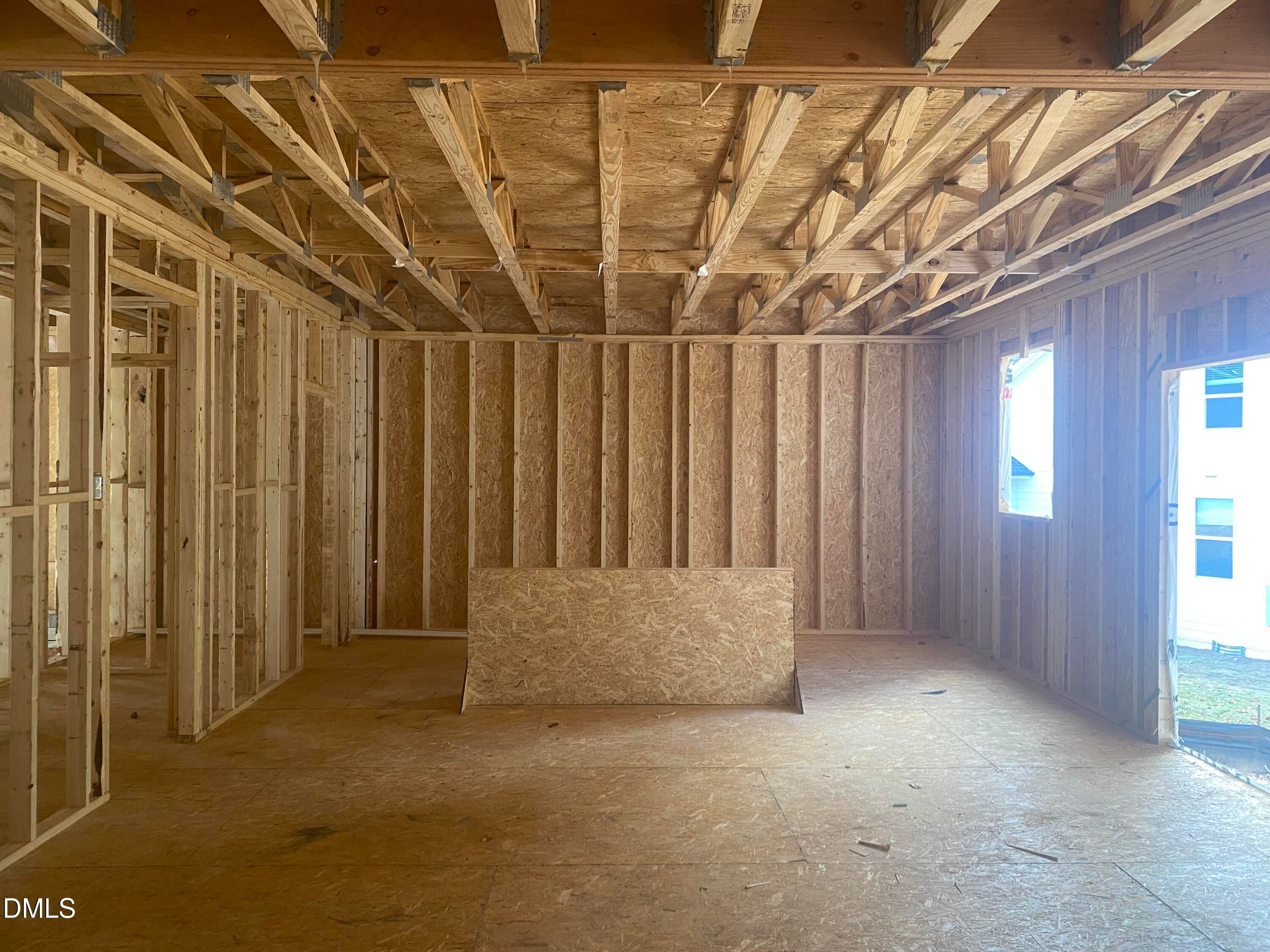 Unfinished interior framing with wooden studs, beams, and plywood floors in Davidson Homes Crawford B, Raleigh, NC