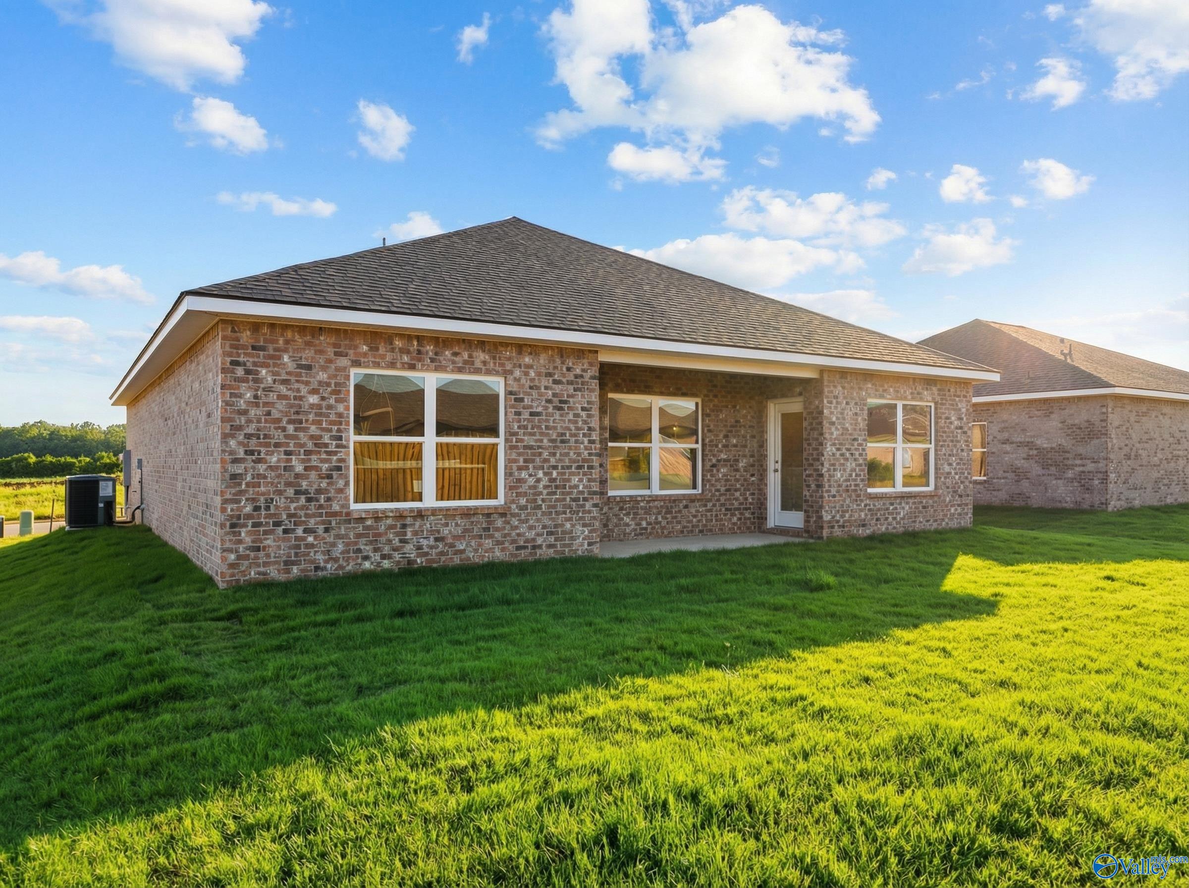 Single-story brick ranch home exterior with shingled roof, large windows, and lush green lawn in Wood Trail, Toney, Alabama